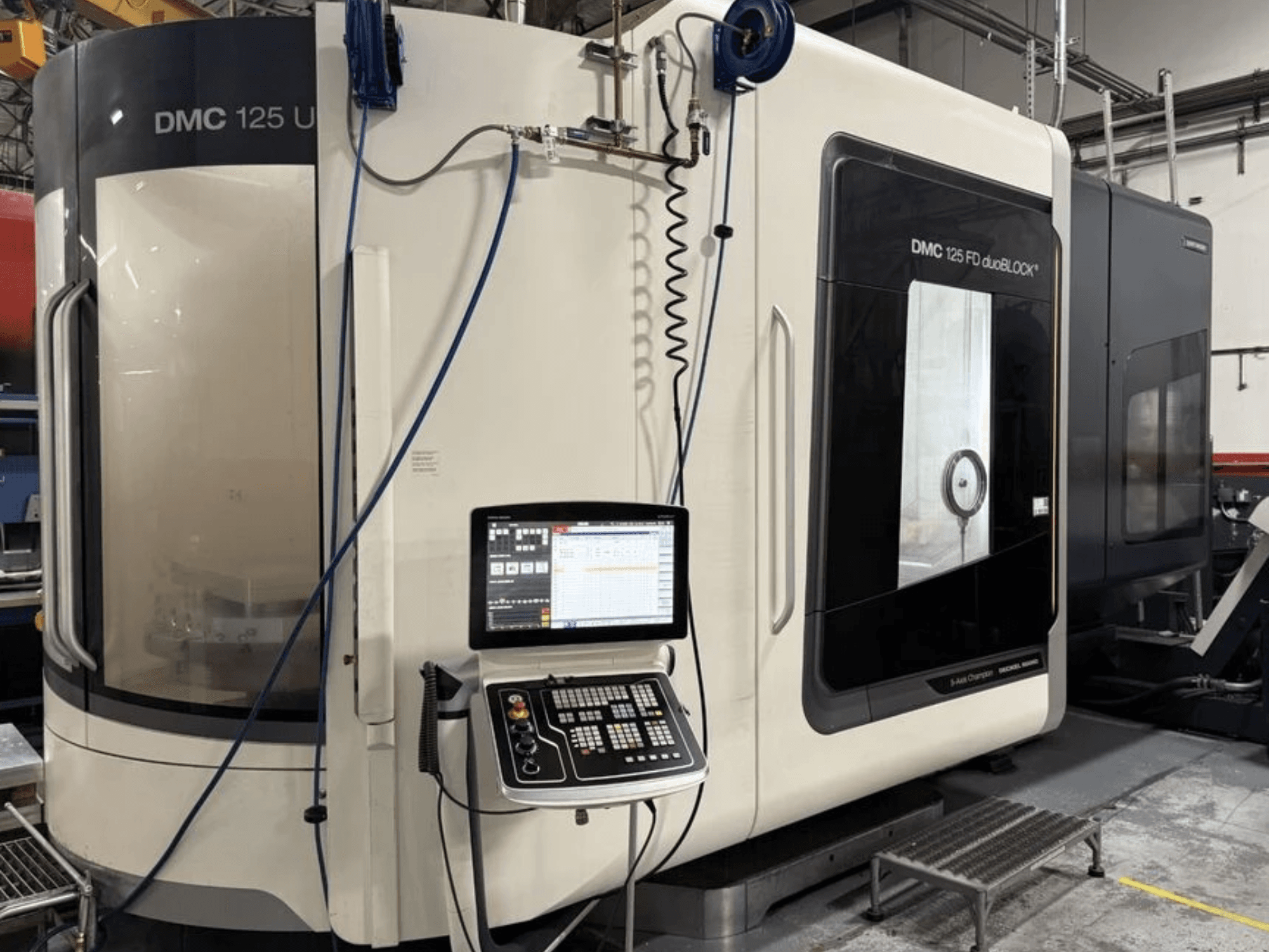 Універсальний обробний центр DMG MORI DMC 125 U duoBLOCK, вид спереду з панеллю керування та відбиваючими поверхнями.