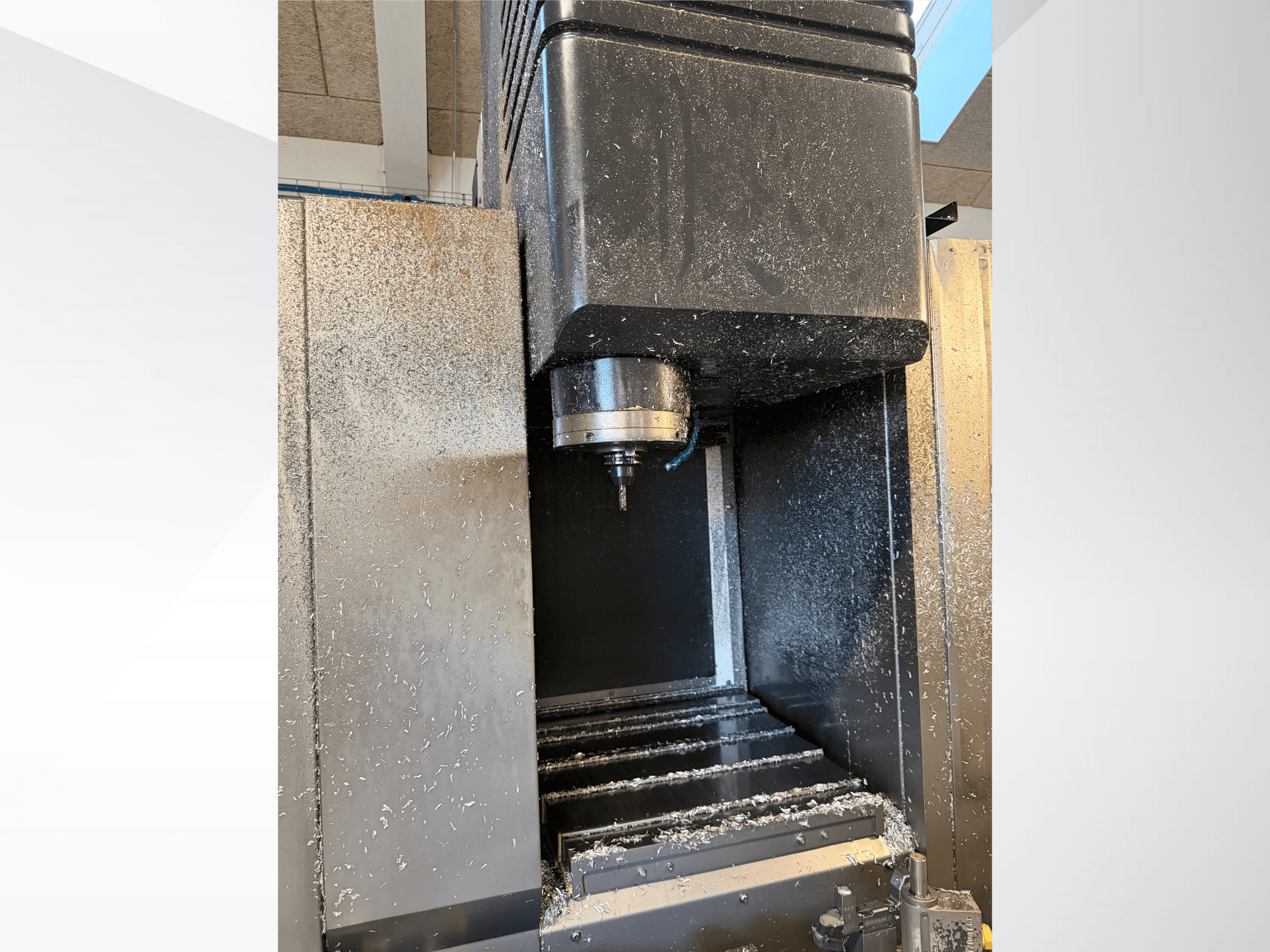 Вертикальний обробний центр Mazak VTC 300C II, вид спереду, на якому видно шпиндель та стружку, що утворилася в процесі обробки.