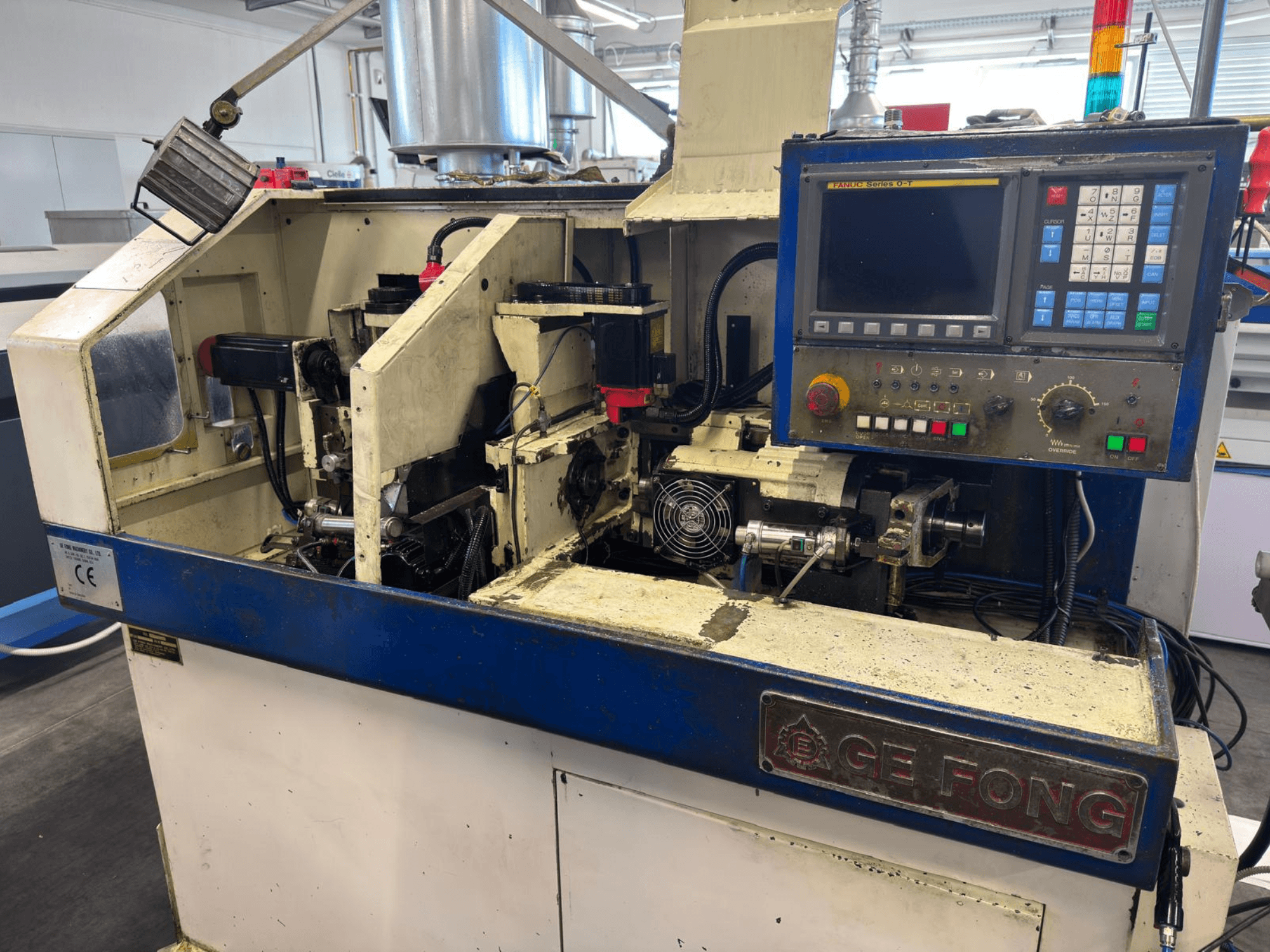 Промислова машина GE FONG у вигляді спереду, показуючи внутрішні компоненти, панель управління та робочі частини.