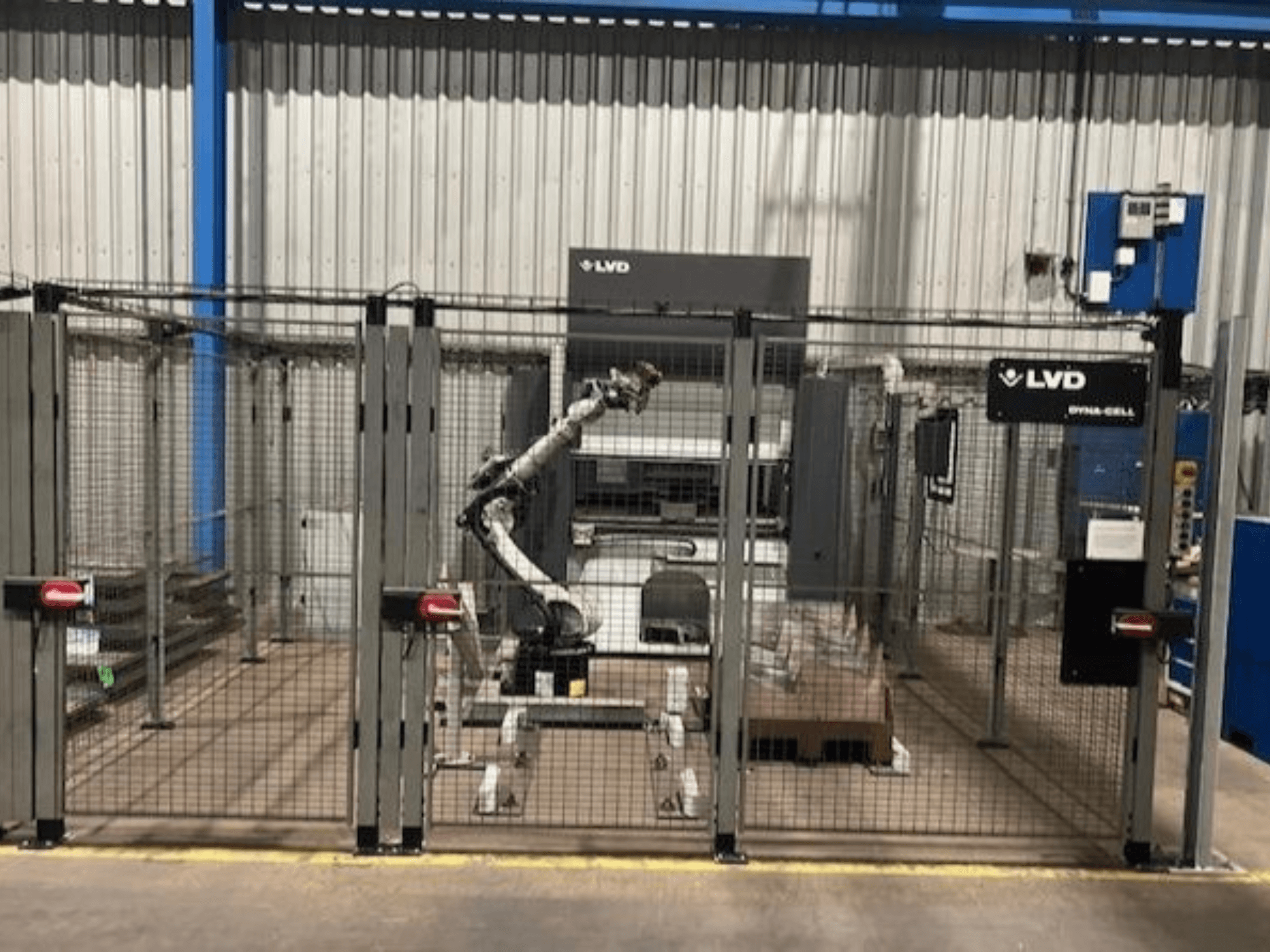 Роботизована робоча станція LVD Dyna-Cell в огородженому корпусі, вид спереду, з роботизованою рукою і панеллю керування.