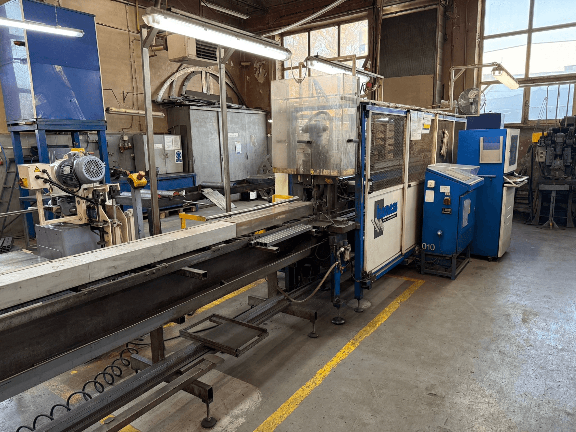 Промисловий цех з синьою машиною Haweas, вид збоку, що показує конвеєр та обладнання у великому, добре освітленому приміщенні.