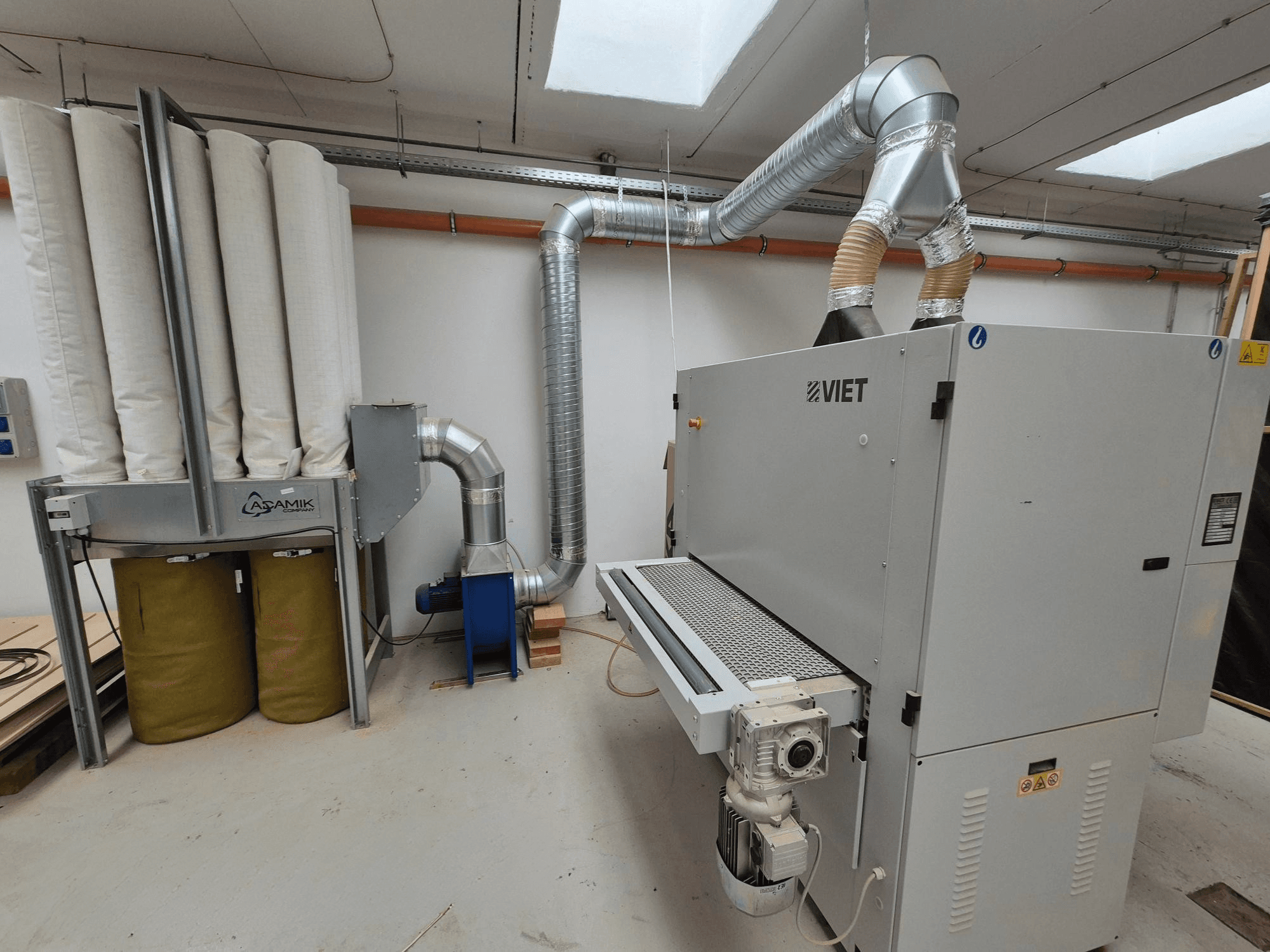 В'єтнамська система пиловідведення з циліндричними фільтрами та сріблястим вихлопом, вид спереду в умовах майстерні.