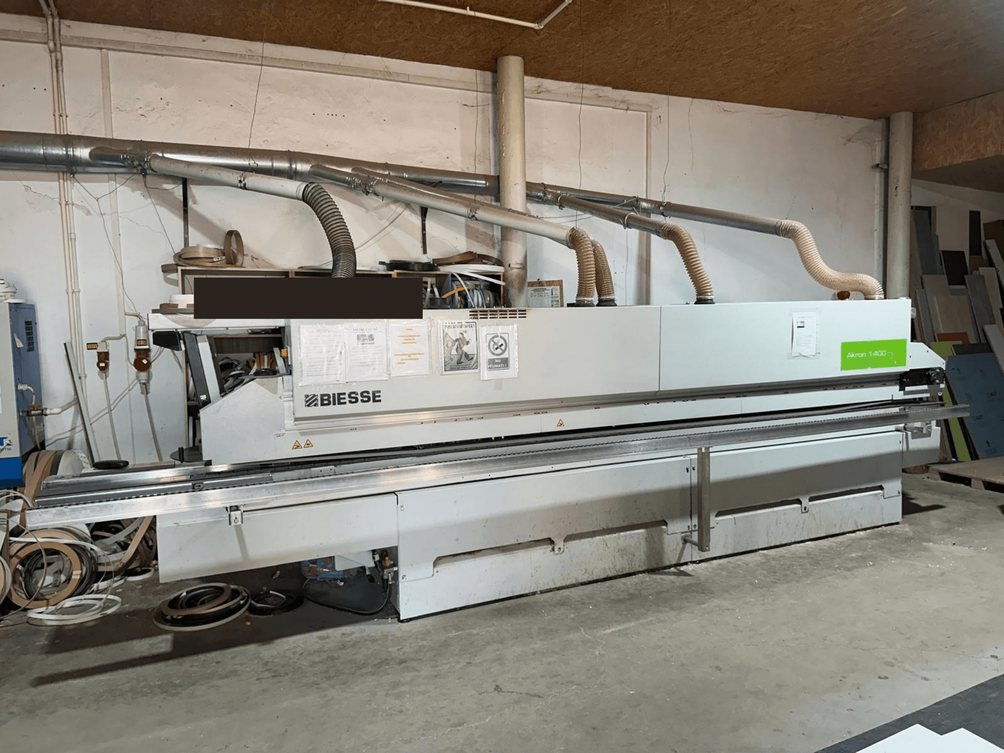 Кромкооблицювальна машина BIESSE AKRON 1440 A, вид спереду, з виднією панеллю управління та елементами системи пиловідведення в умовах цеху.