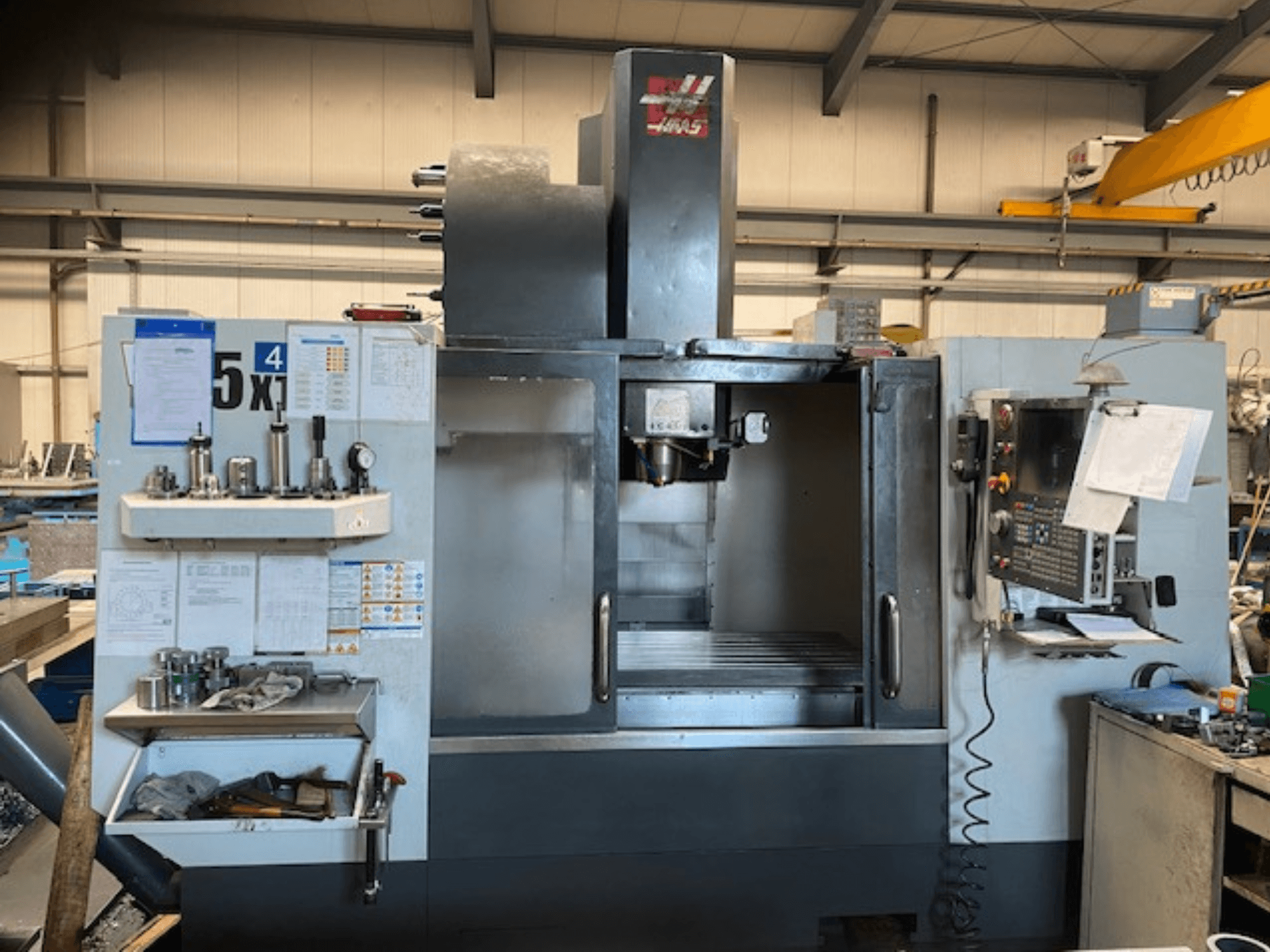 Вертикальний обробний центр Haas VF-5, вид спереду, демонструє панель керування, місце для зберігання інструменту та зону шпинделя.