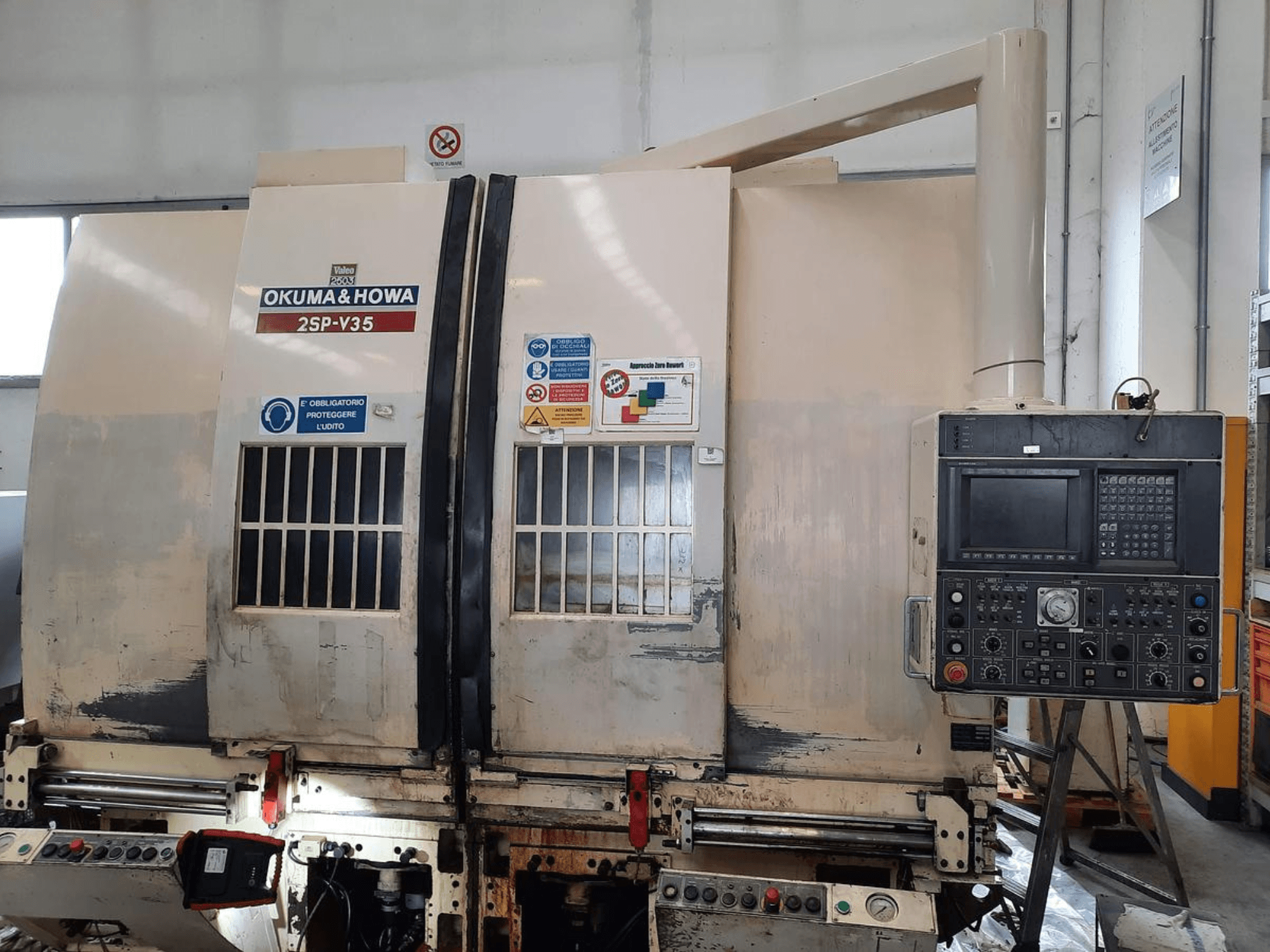 Верстат з ЧПК OKUMA & HOWA 2SP-V35, вид спереду, з панеллю керування з різноманітними кнопками та етикетками безпеки.