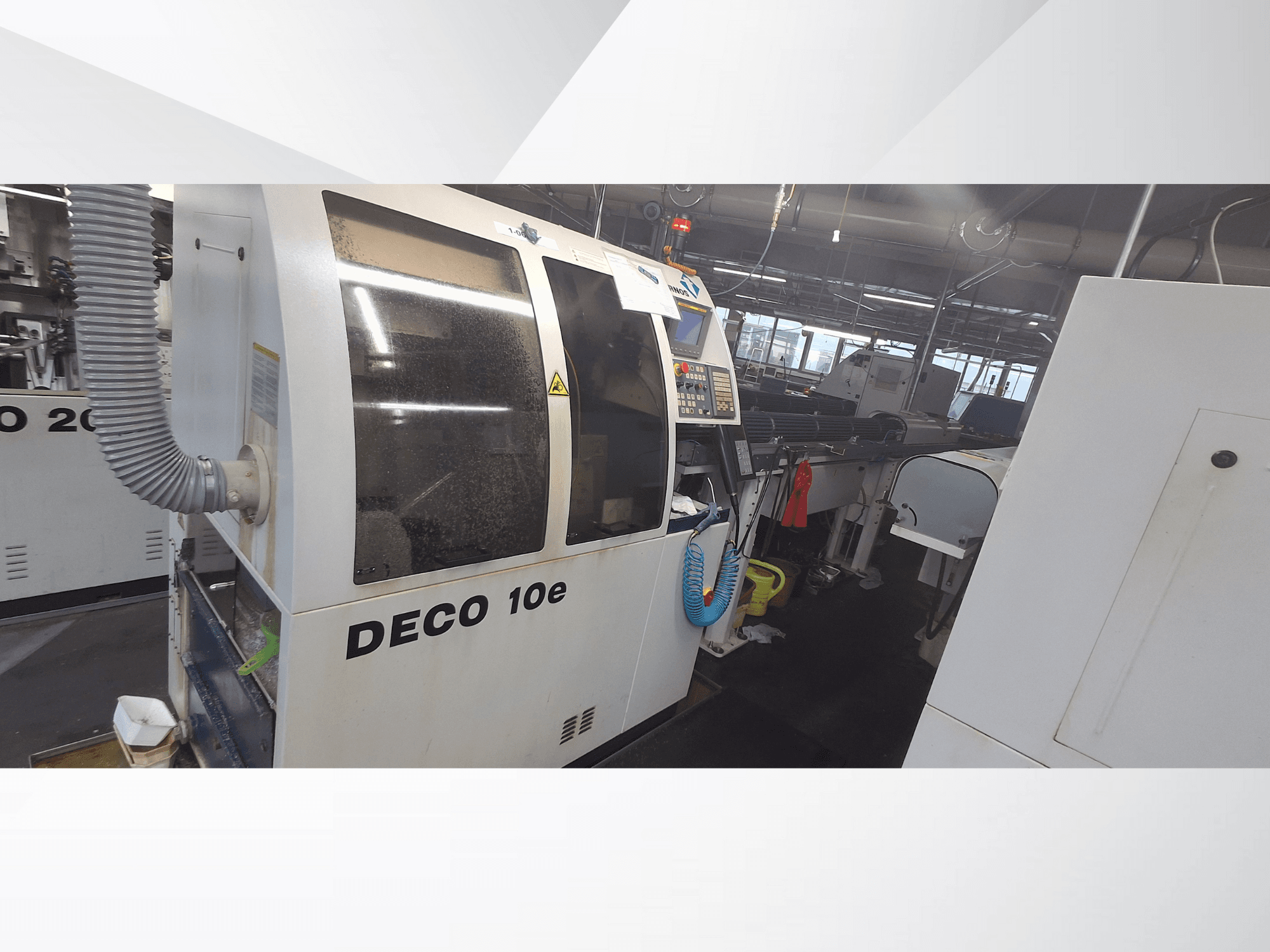 Верстат DECO 10e в майстерні; вид збоку, де видно панель управління і вентиляційний шланг, на задньому плані розмиті механізми.