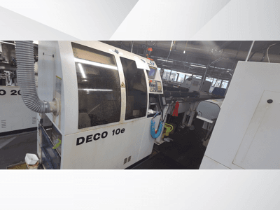 Верстат DECO 10e в майстерні; вид збоку, де видно панель управління і вентиляційний шланг, на задньому плані розмиті механізми.
