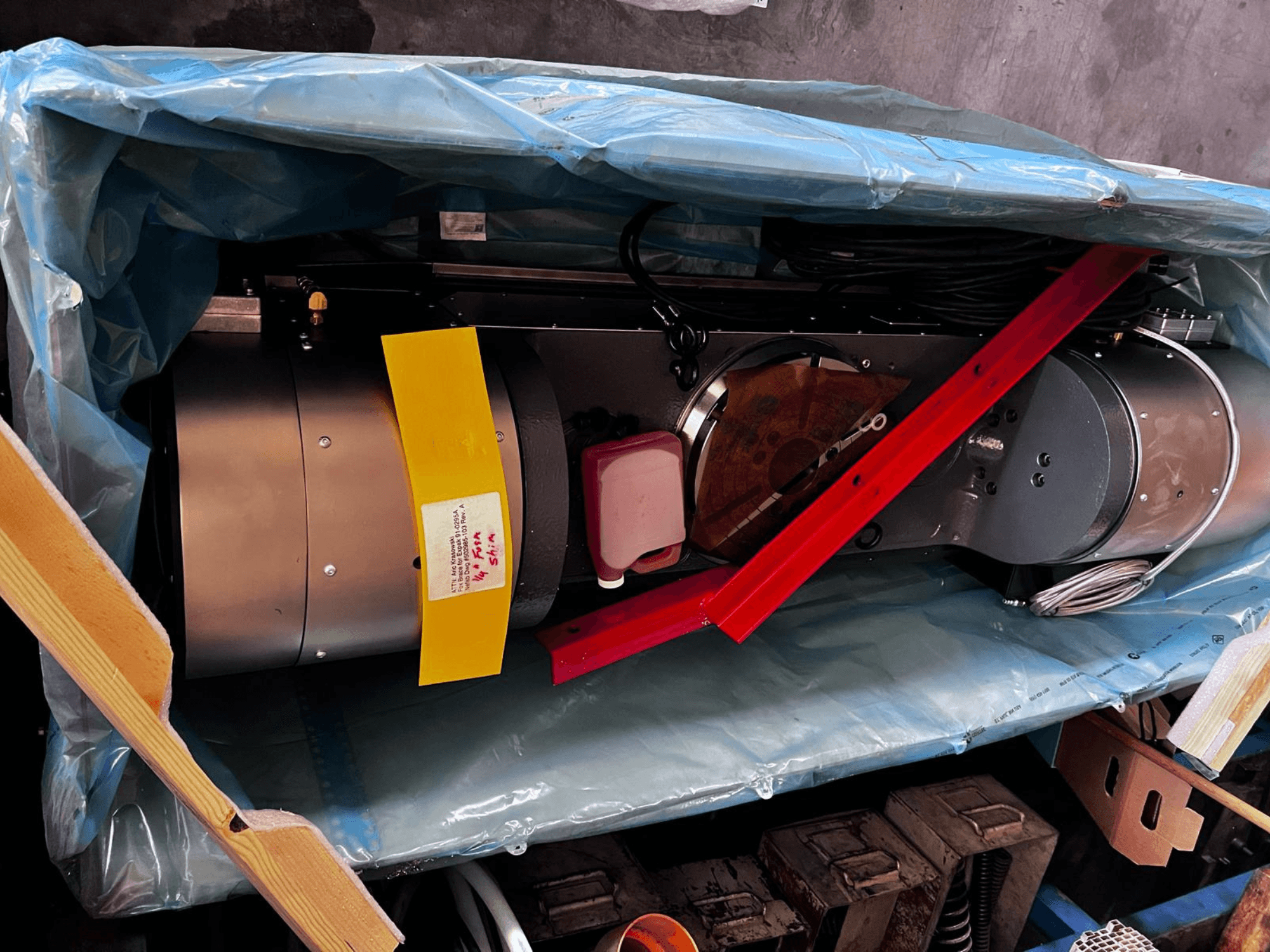 Моторний пристрій, який частково видно з упаковки, має сріблястий зовнішній вигляд, кольорові датчики та червону опорну скобу.