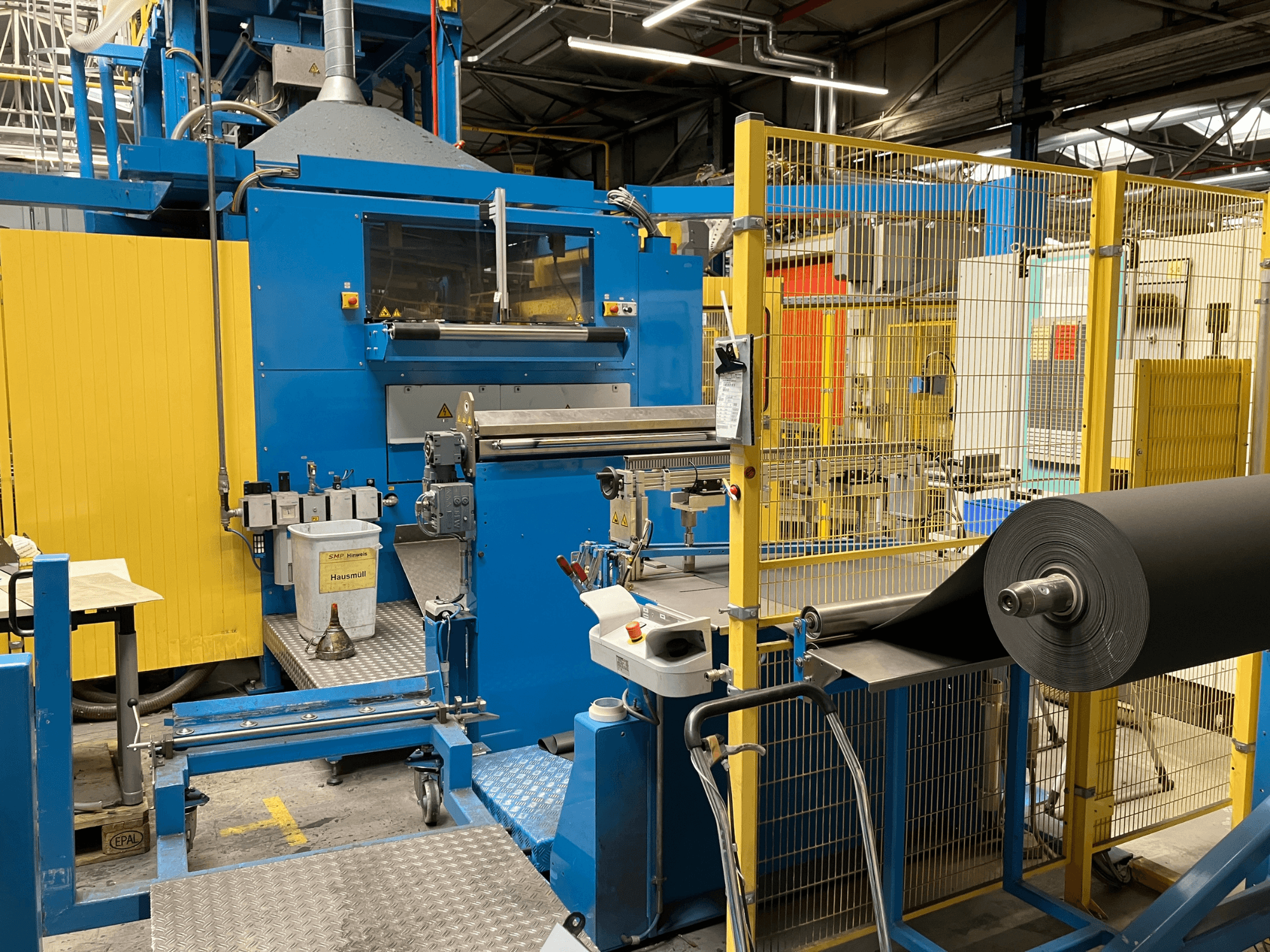Машина для переробки пластмас KIEFEL KLS 86/235, вид спереду, з рулоном чорного матеріалу та панеллю керування.