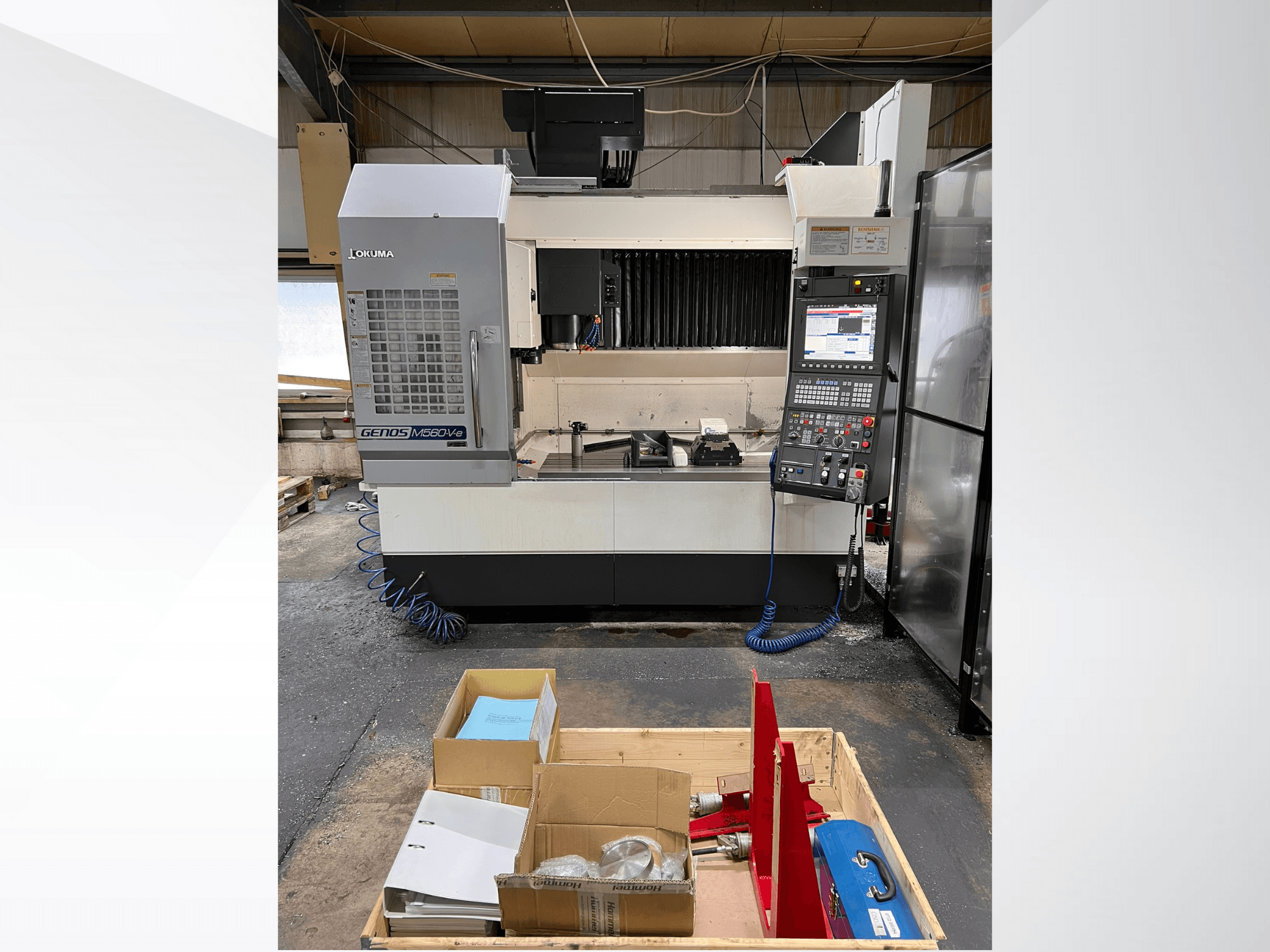 Вертикальний обробний центр Okuma GENOS M460V-5, вид спереду, з видимою панеллю керування та інструментами на робочому столі.