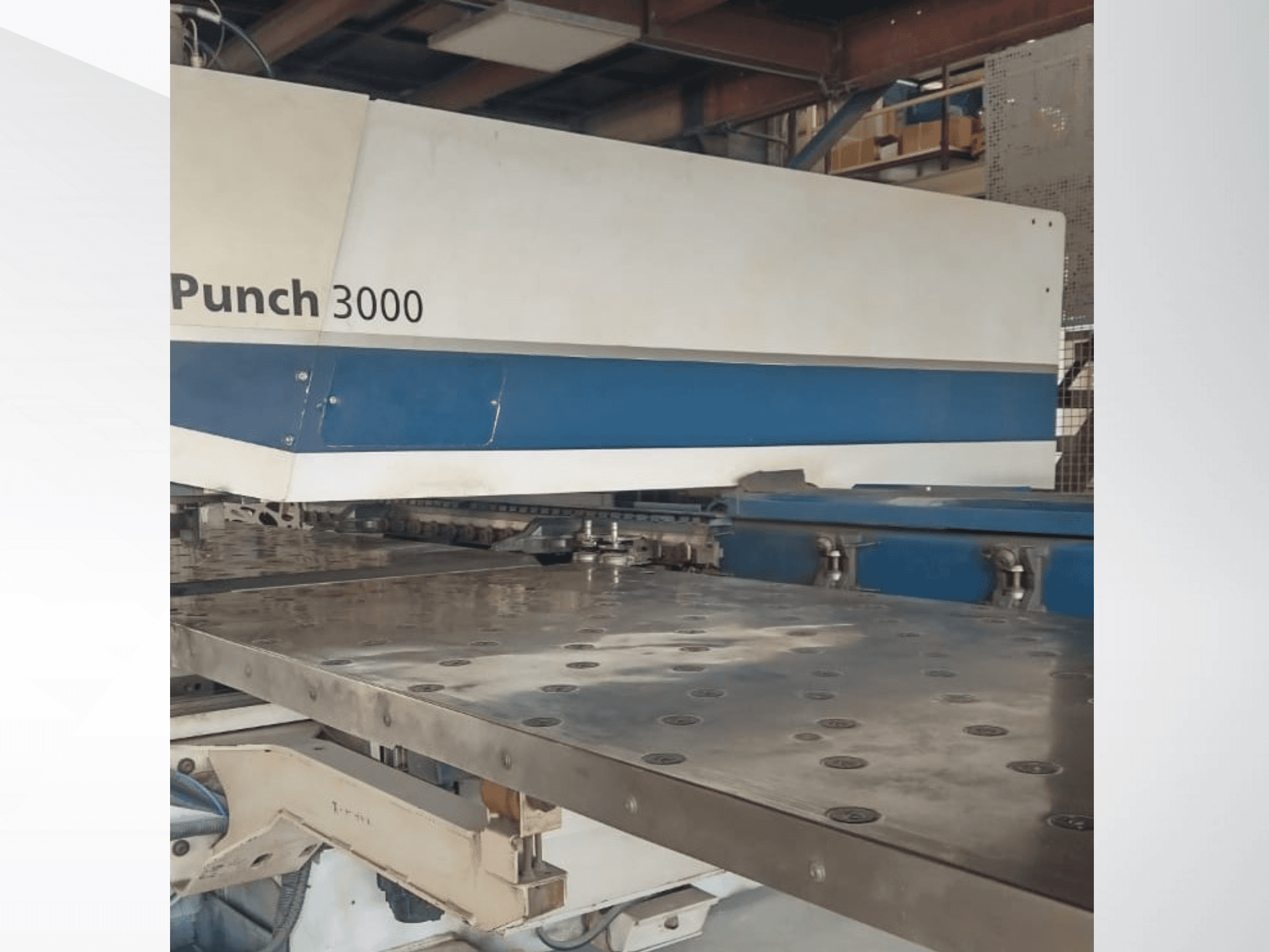 Верстат Punch 3000 в майстерні, вид спереду, демонструє велику плоску металеву поверхню з численними перфораційними отворами.