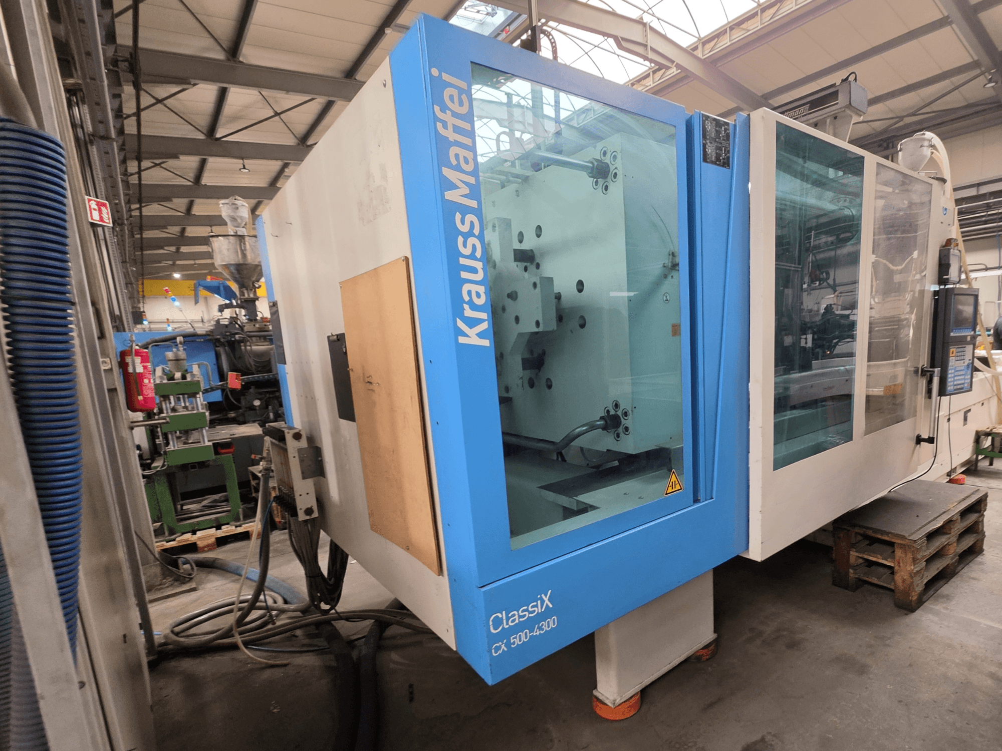 Гідравлічний термопластавтомат Krauss Maffei 500-4300 CX, вид збоку, демонструє панель керування та робочі компоненти.
