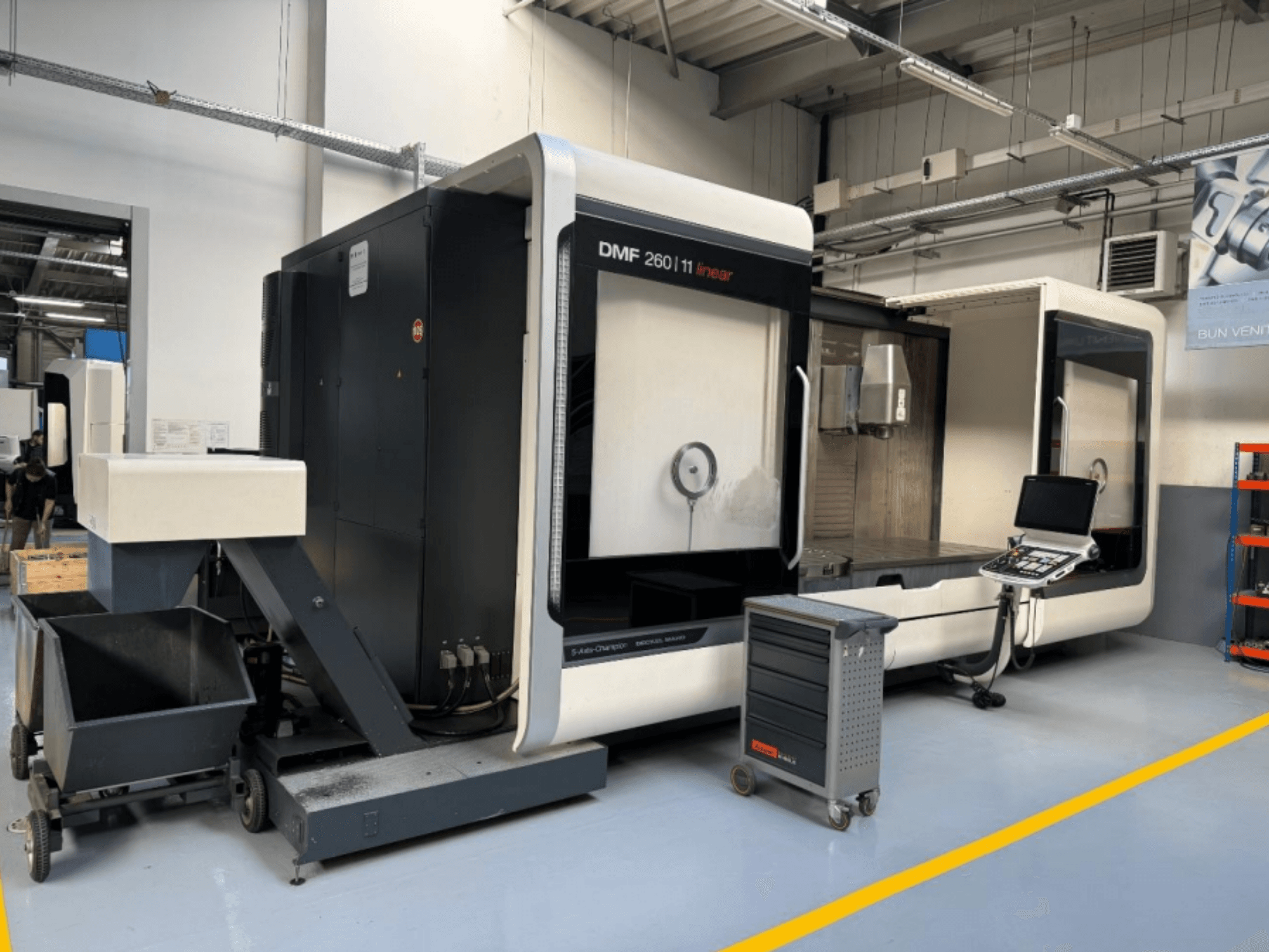 Лінійний фрезерний верстат DMG MORI DMF 260 показаний спереду, з панеллю керування інструментом і мобільним візком для інструментів поруч.