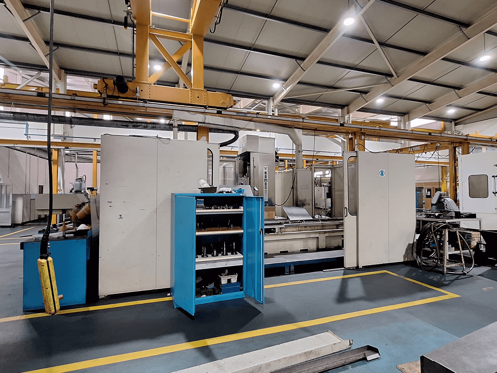 Портальний фрезерний верстат Rambaudi RX 1250, вид спереду зі сховищем для інструментів, у просторому промисловому робочому приміщенні.