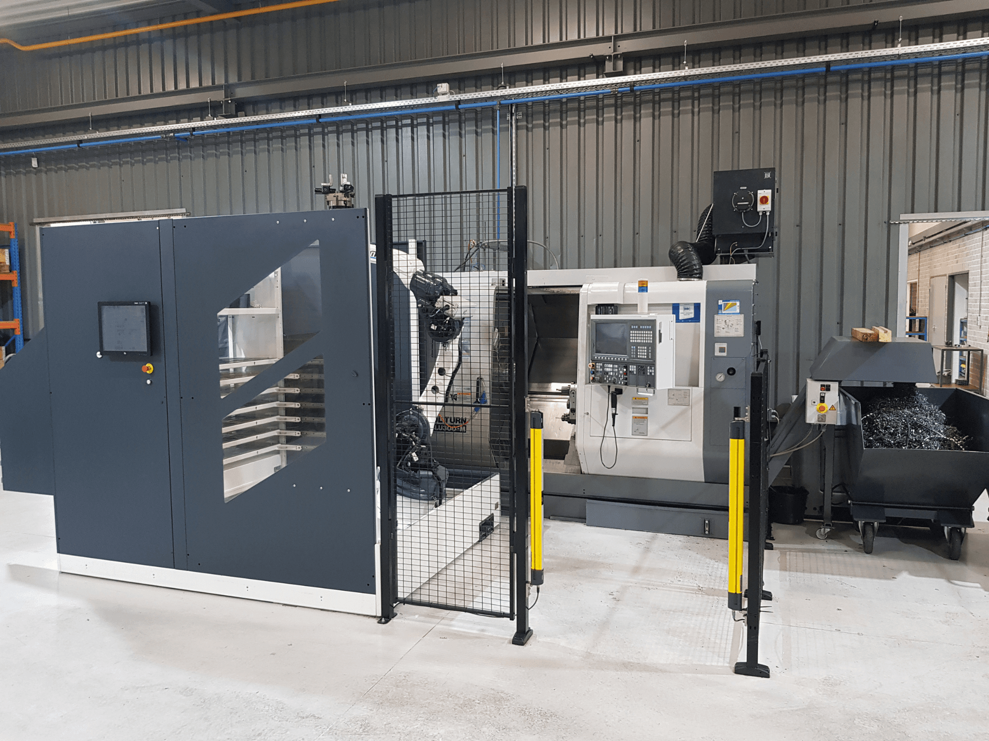 Автоматизований токарний верстат з ЧПК ALTURN показаний у заводських умовах; вид спереду з панеллю керування та захисною огорожею.