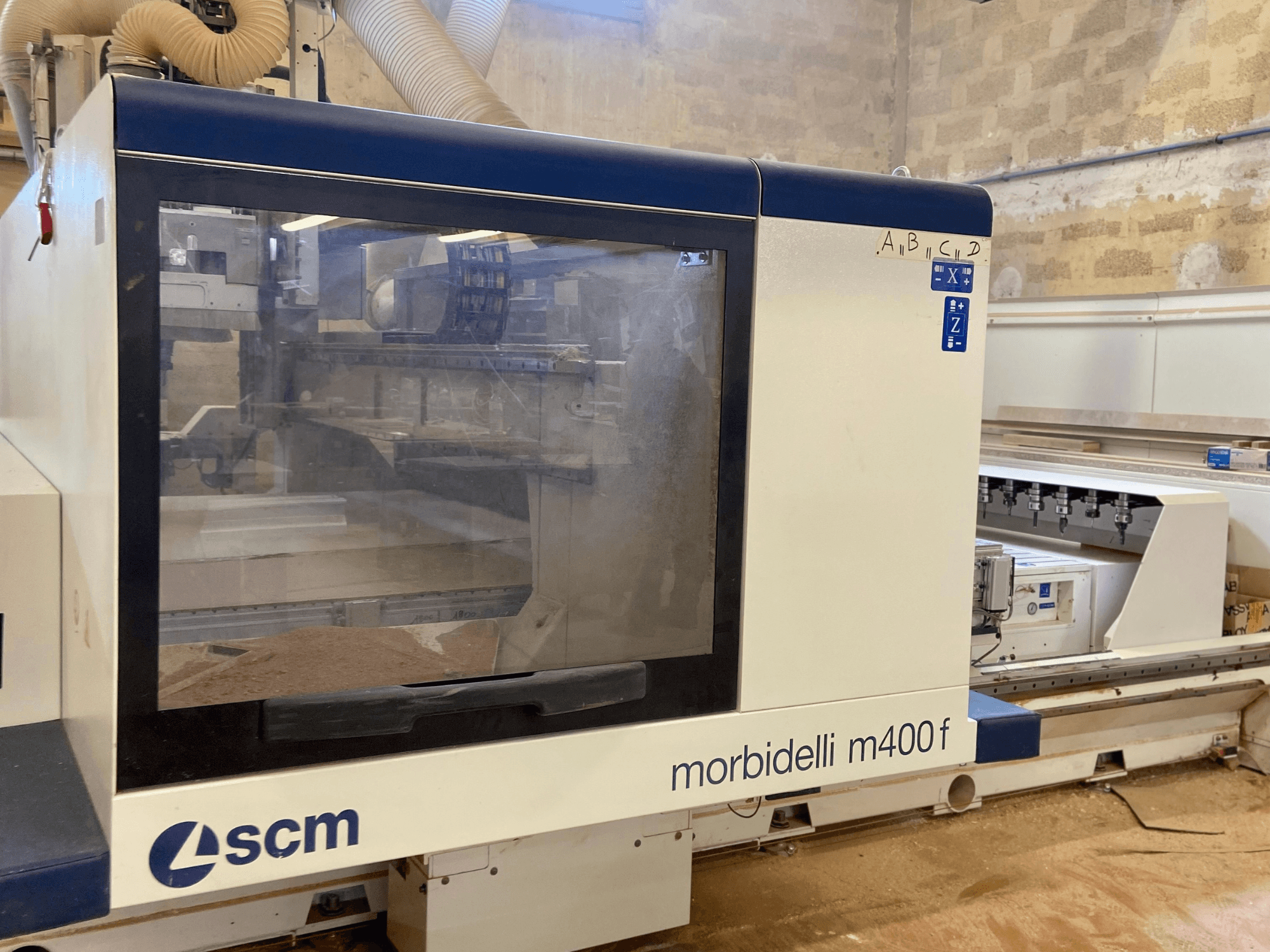 Верстат з ЧПУ SCM Morbidelli M400F, вид спереду, з панеллю керування та видимою тирсою на підлозі.