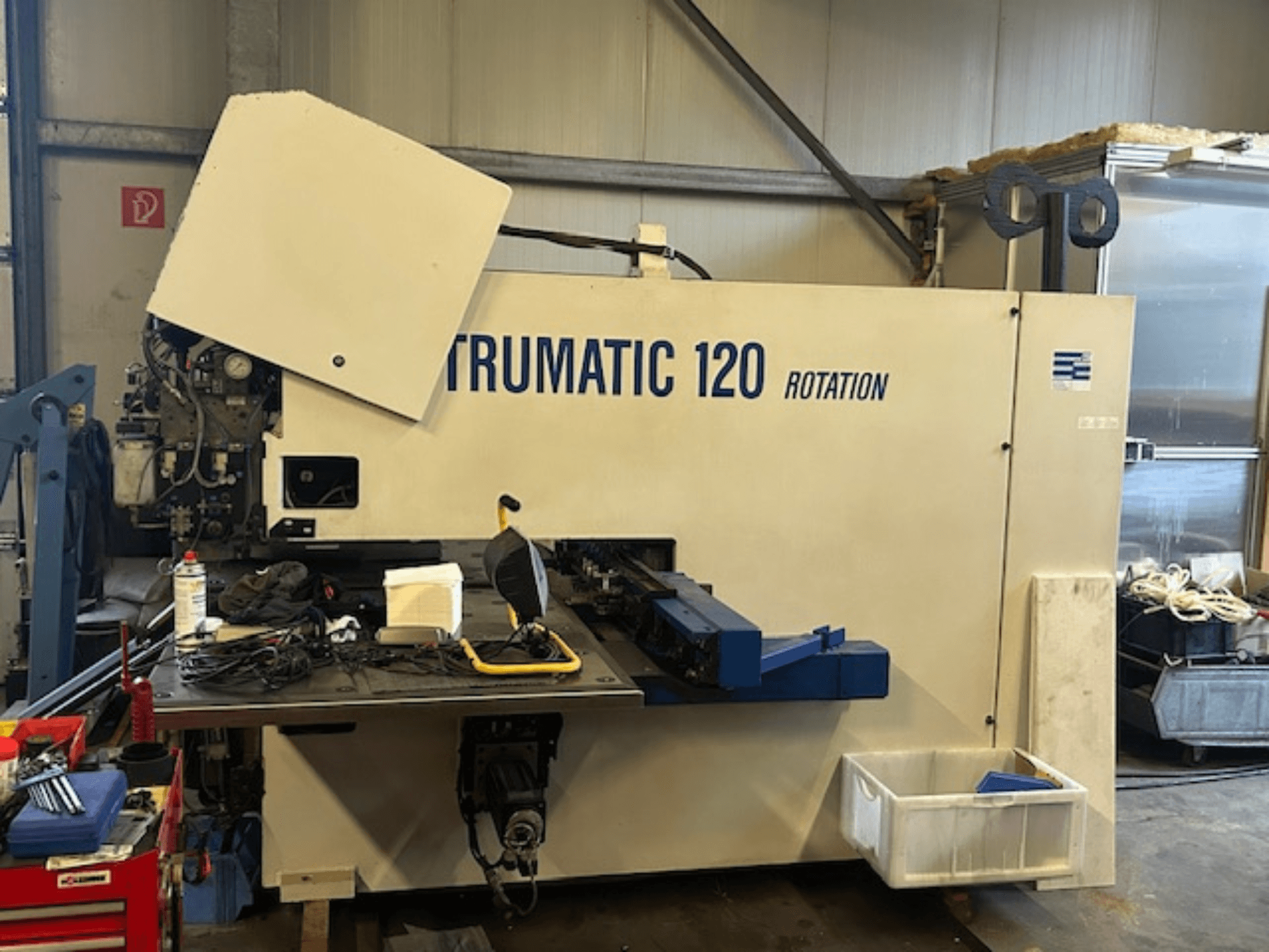 Пробивний верстат TRUMPF Trumatic 120R з ЧПУ в майстерні, вид спереду з панеллю керування та інструментами на столі.