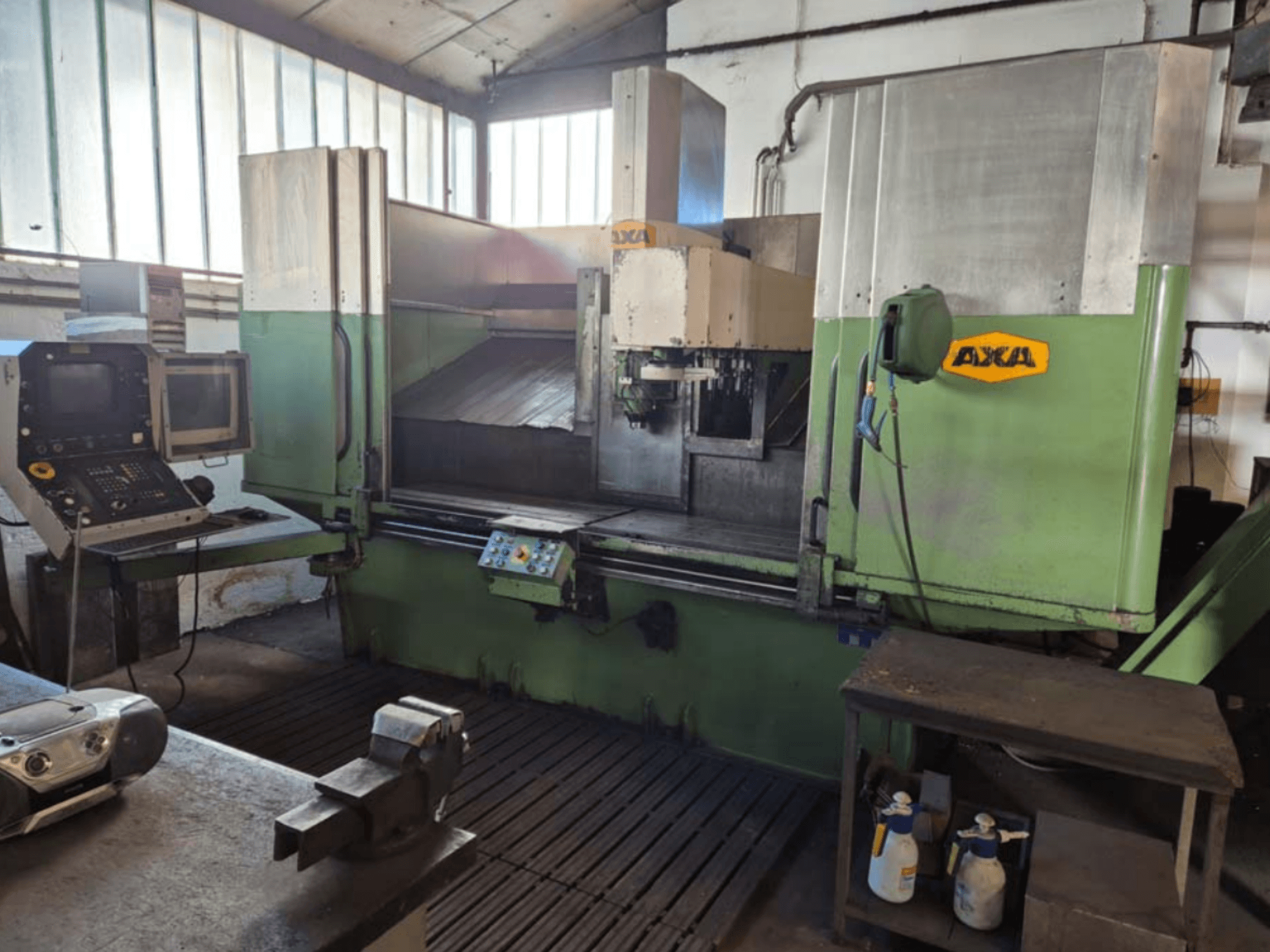 Вертикальний обробний центр AXA VSC-2M, вид спереду, з панеллю керування та робочою зоною з ріжучими інструментами та засобами для чищення.