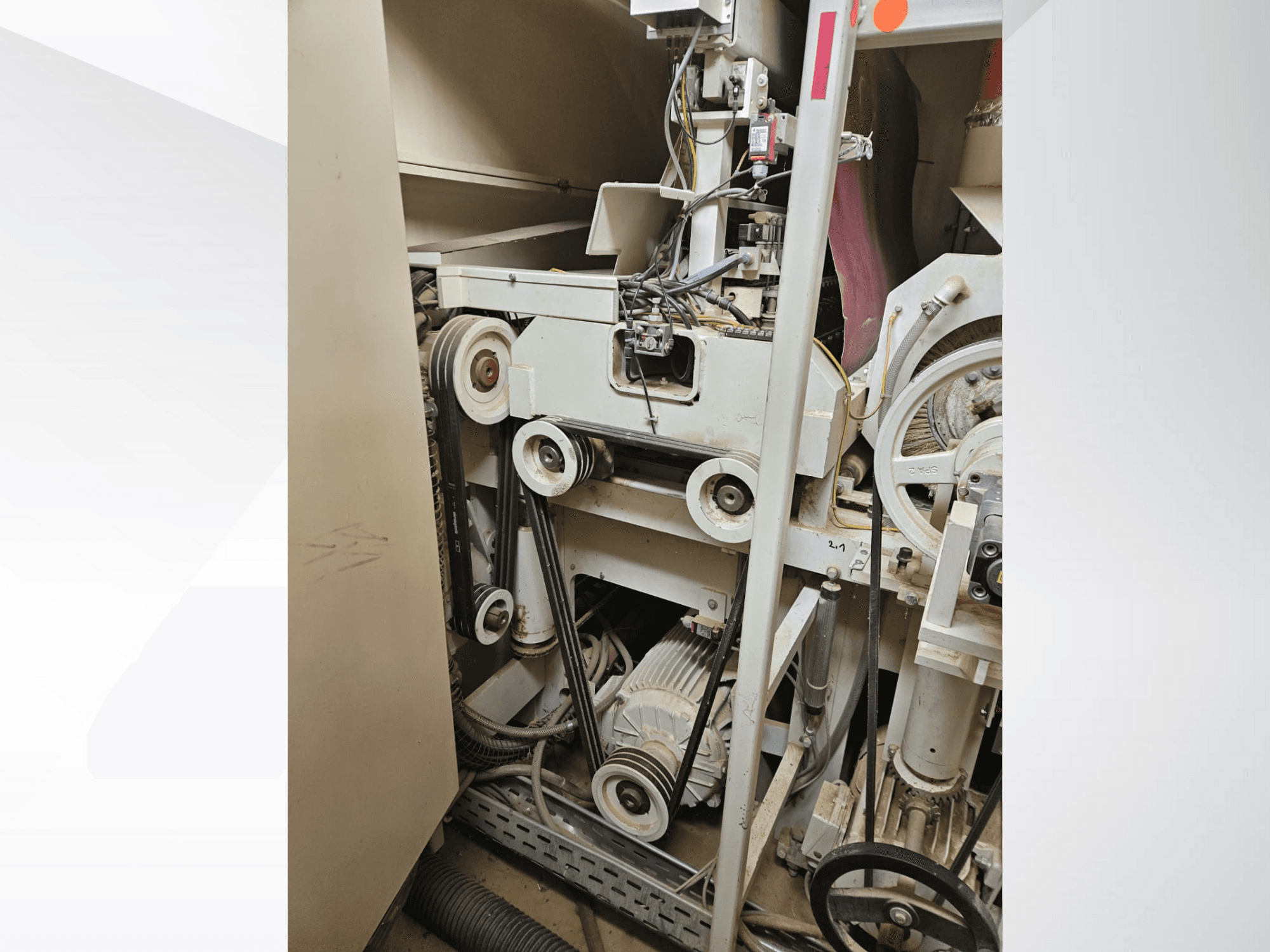 Інтер'єр промислової машини з ременями та шківами, з двигуном та електропроводкою, вид збоку.