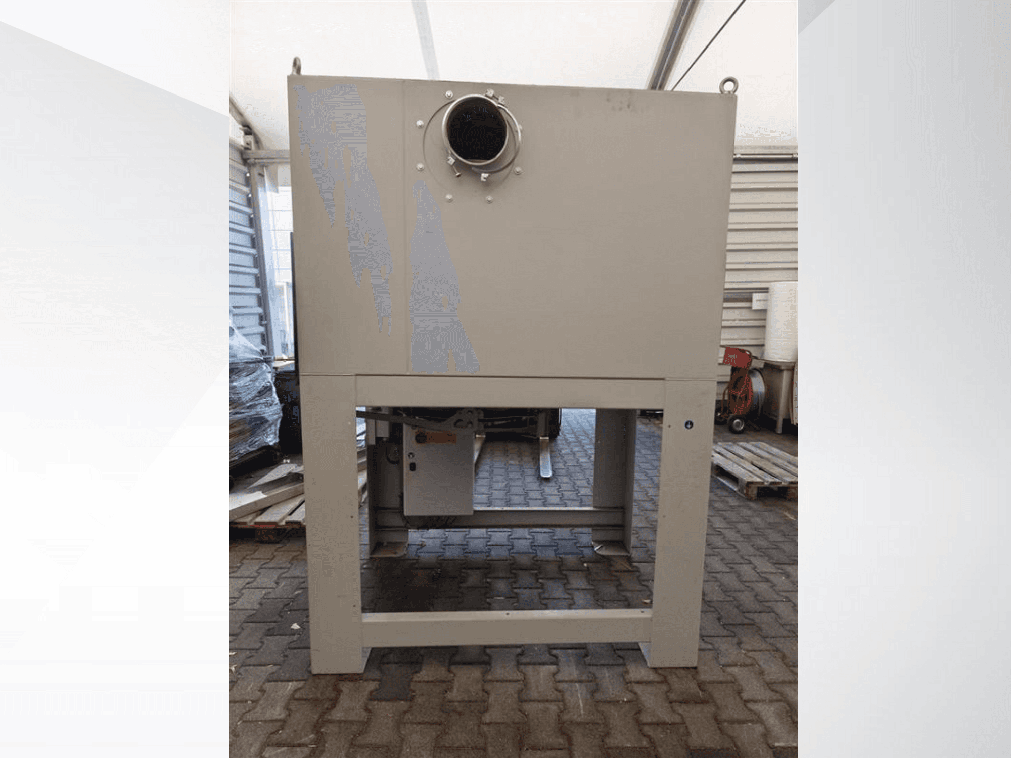 Сірий промисловий пилозбірник спереду, з великим круглим отвором, встановлений на міцній основі.