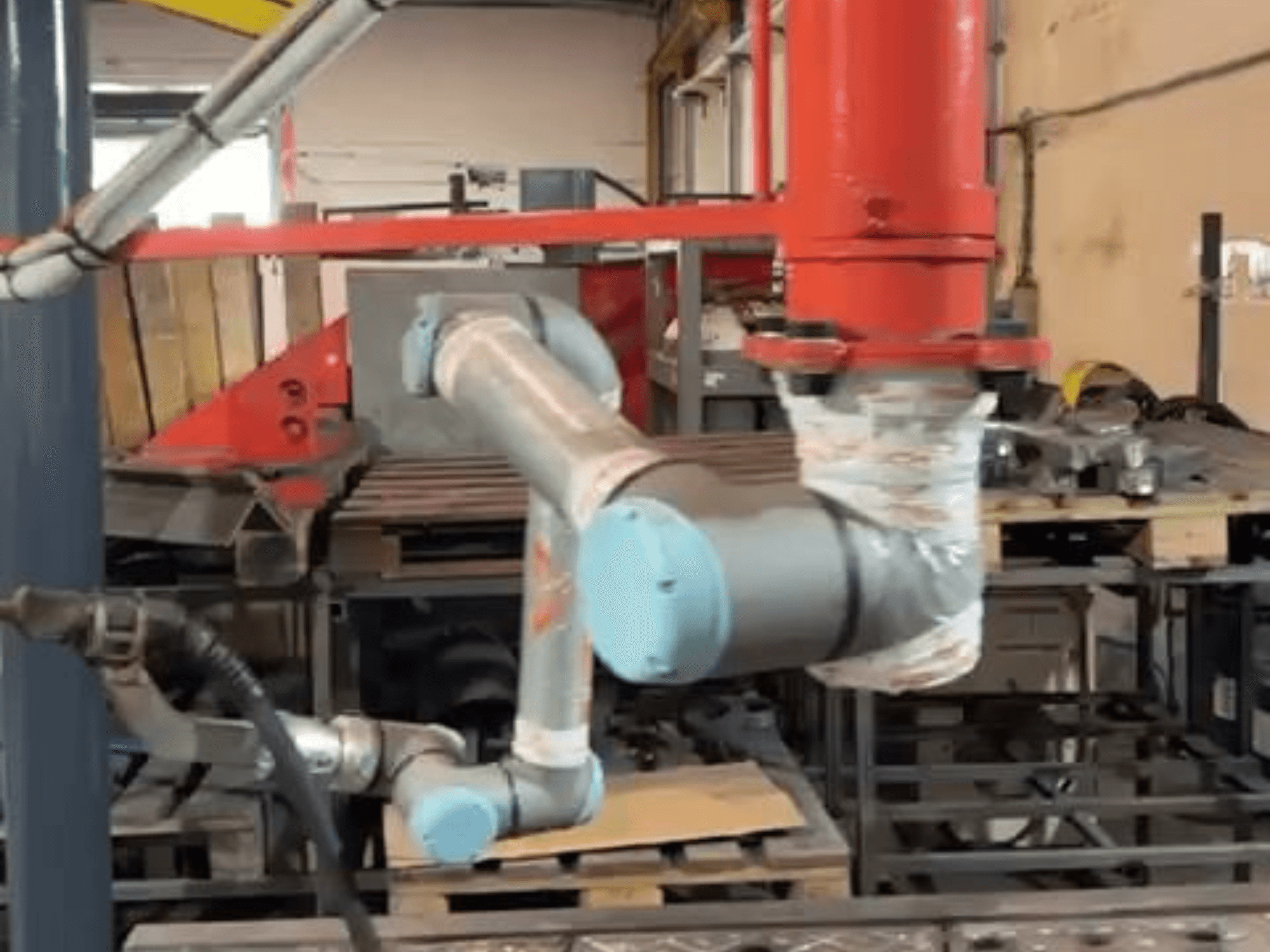 Колаборативний робот Universal Robots UR10e у цеху: вид збоку, на якому видно рухи маніпулятора та суглобів поблизу обладнання.