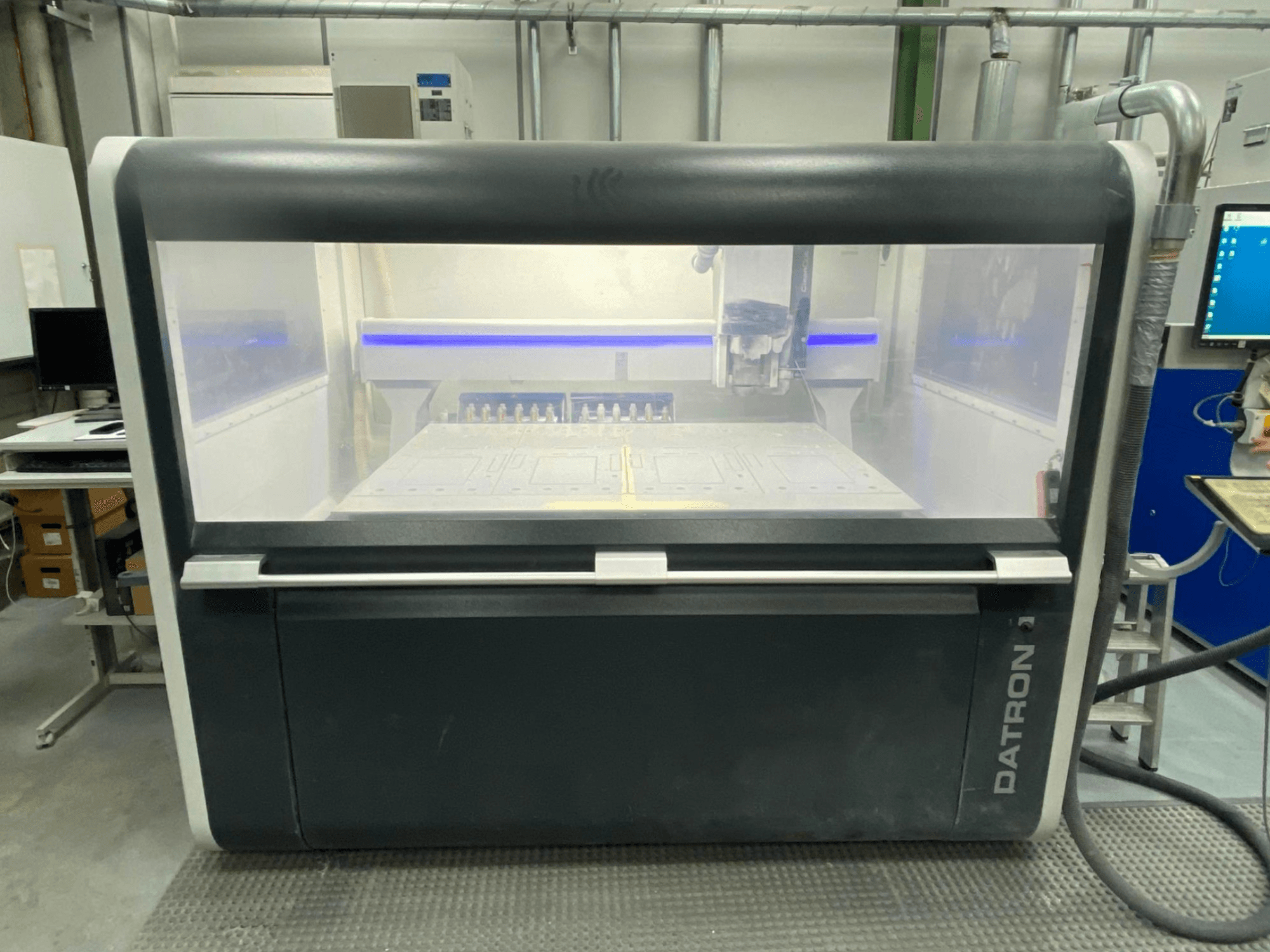 Вертикальний обробний центр Datron MLCube B спереду, з прозорим корпусом і панеллю керування.