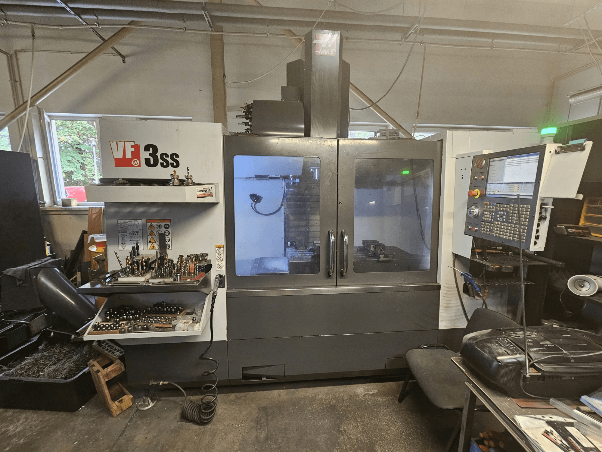 Вертикальний обробний центр Haas VF-3SS у цеху, вид спереду, на якому видно панель управління та відсік для зберігання інструментів.