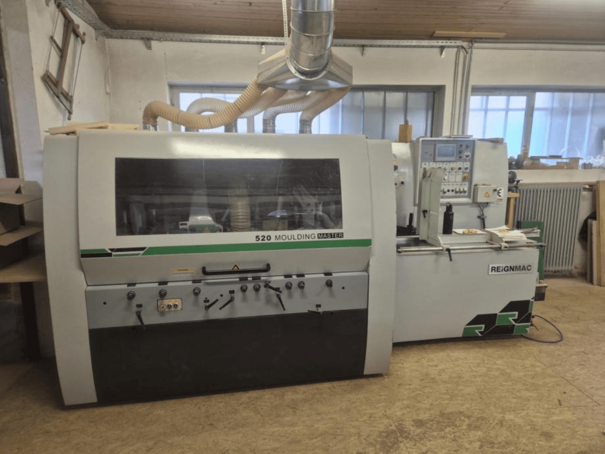 Вид спереду на стругальний верстат REIGNMAC 520 MOULDING MASTER, демонструє панель керування, подавальні ролики та систему відсмоктування пилу.
