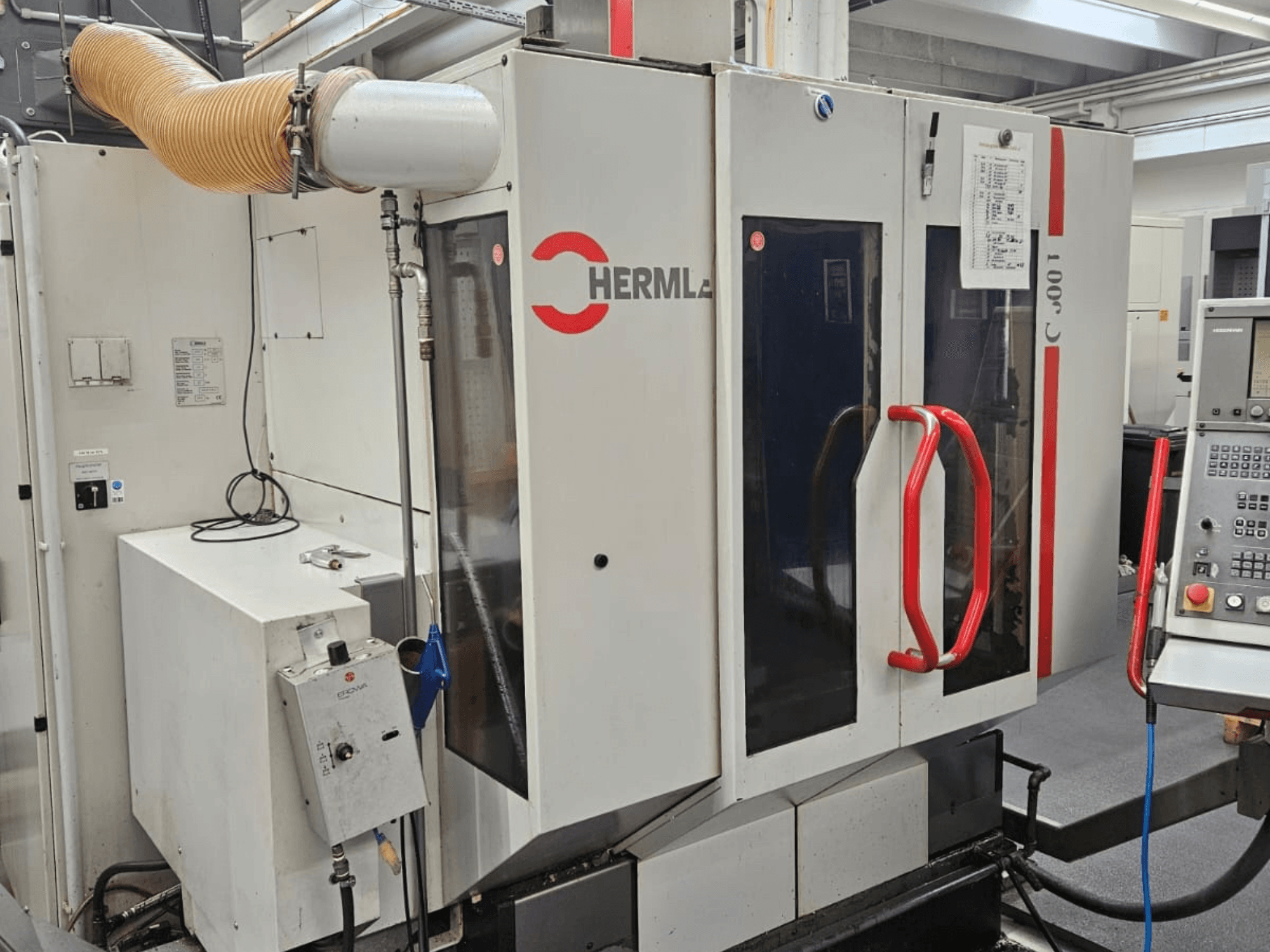 Універсальний обробний центр HERMLE C 600 U спереду, з панеллю керування та червоними ручками на дверях.