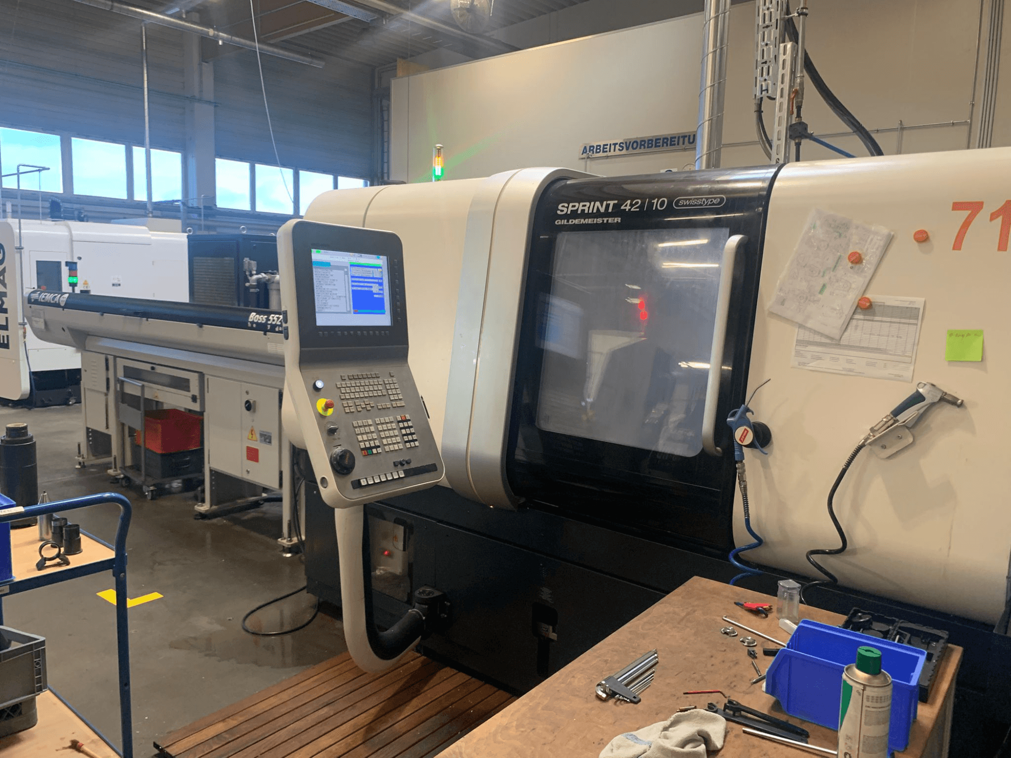Лінійний токарний верстат DMG MORI Sprint 42/10 швейцарського типу, вид спереду, з панеллю керування та захаращенням робочого простору.