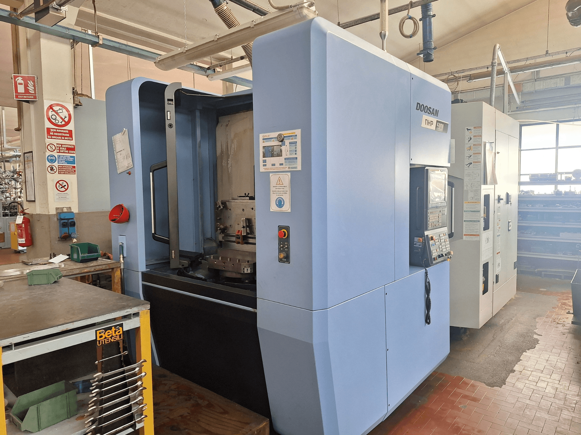 Горизонтальний обробний центр DOOSAN NHP 5000 в майстерні, вид збоку, що демонструє панель керування та зону обробки.