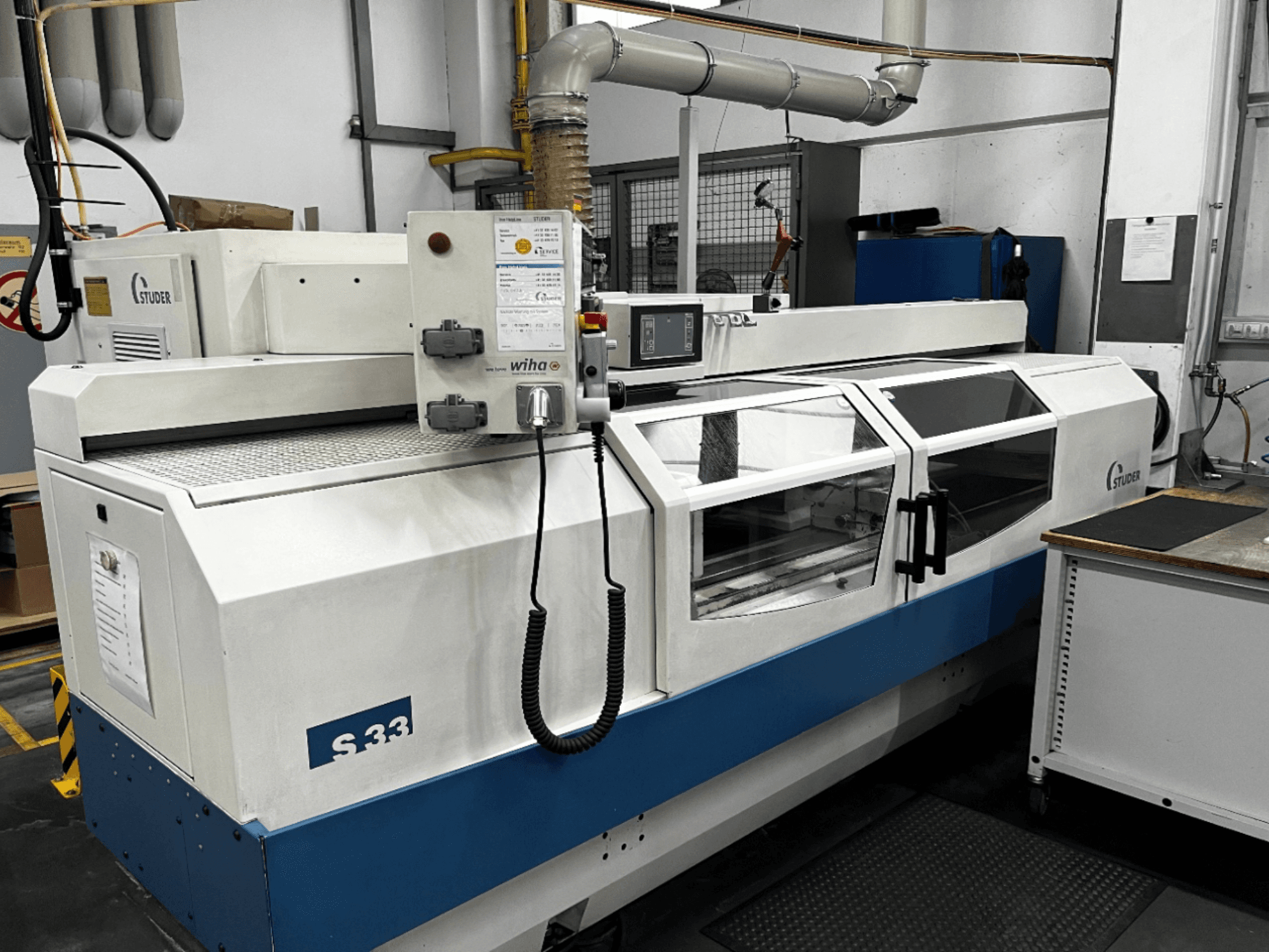 Циліндричний шліфувальний верстат з ЧПК STUDER S33, вид спереду; оснащений панеллю керування та скляними захисними дверцятами. Промислове застосування.
