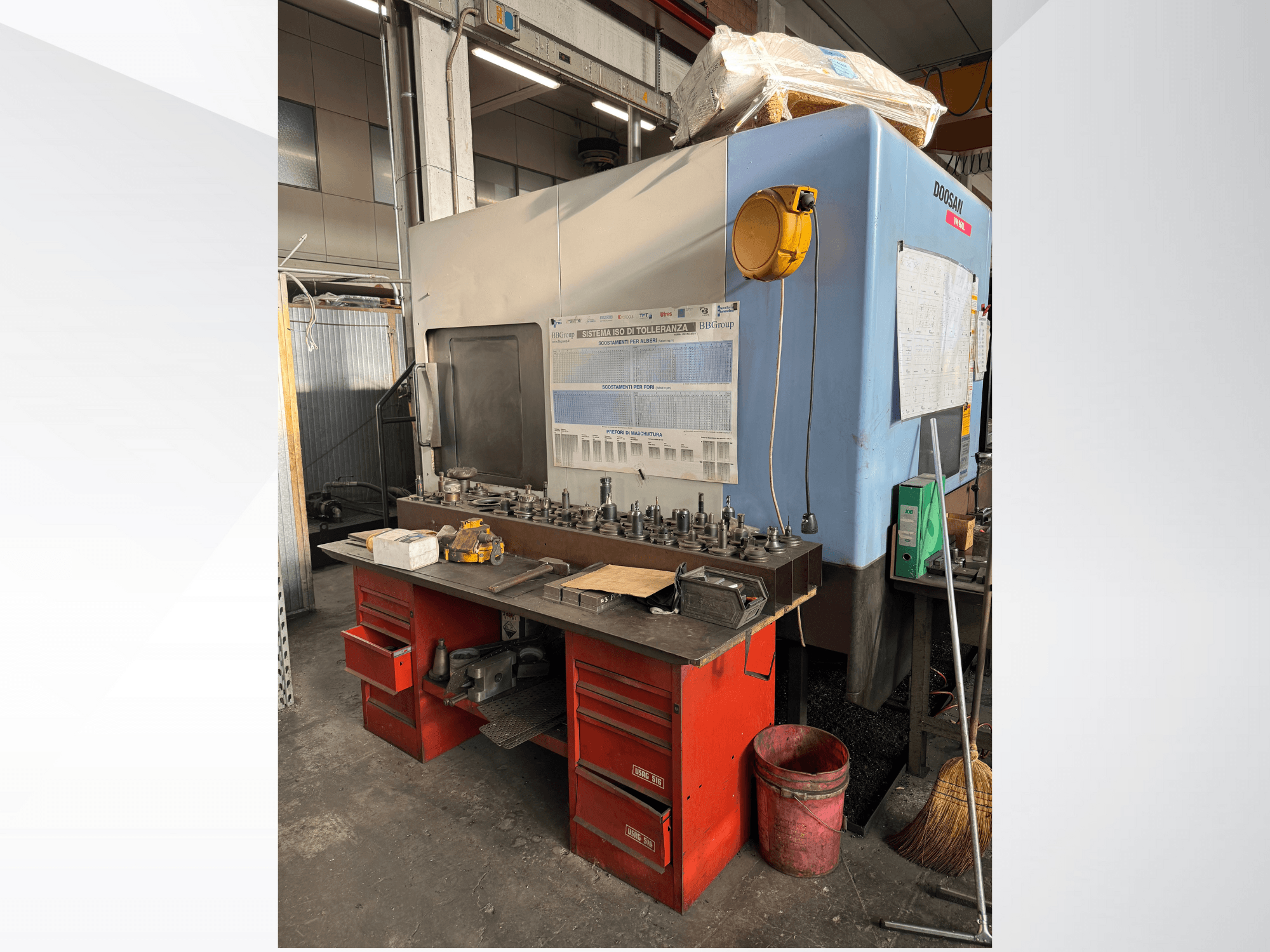 Обробний центр Doosan з червоним робочим столом і сховищем для зберігання інструментів та обладнання, вид спереду.