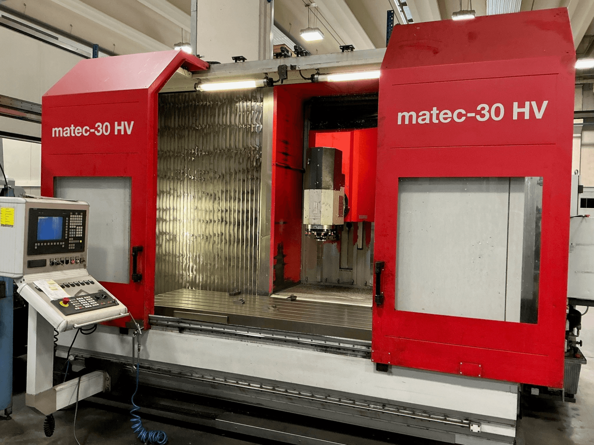 Червоний вертикальний обробний центр Matec 30 HV, вид спереду, з панеллю керування та відкритими дверима, що відкривають зону різання.
