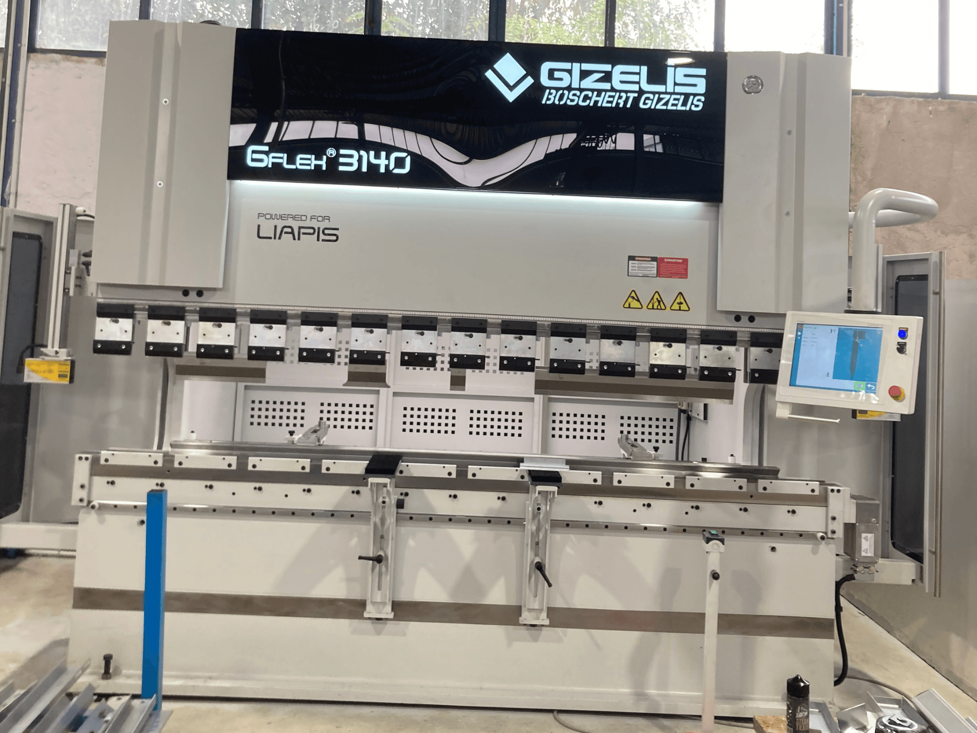 Гідравлічний прес GIZELIS G-FLEX 3140, вид спереду з екраном управління, з декількома інструментами для згинання та етикетками безпеки.