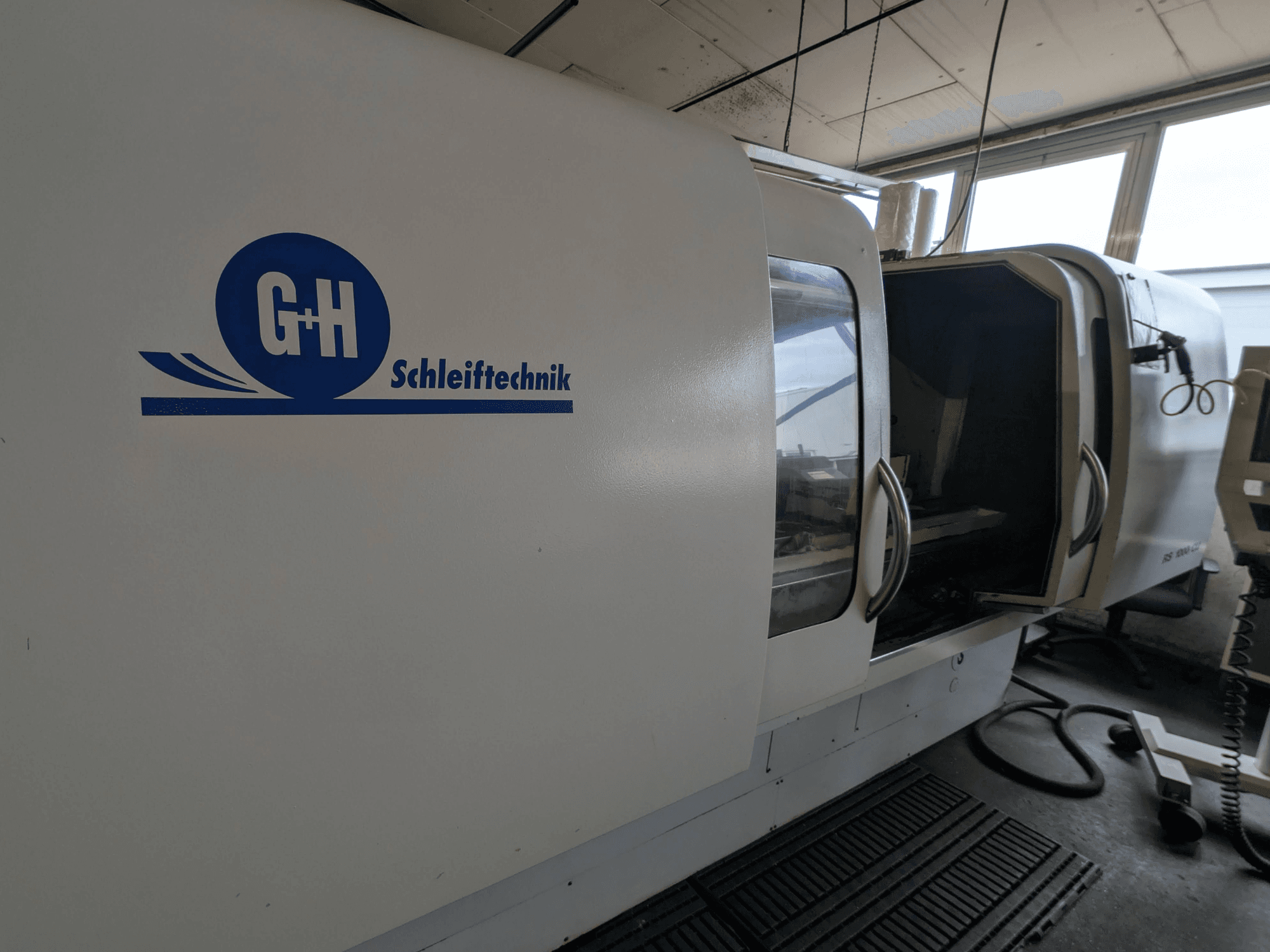 Круглошліфувальна машина GEIBEL & HOTZ RS 1000 CU, вид збоку з панеллю керування та відкритими дверцятами.