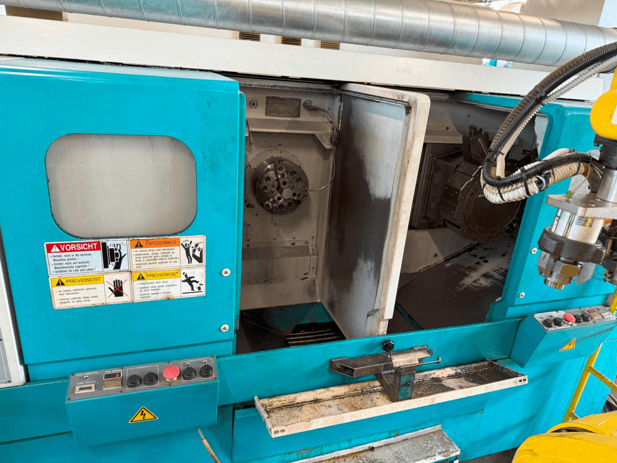 Горизонтальний токарний верстат DOOSAN H310T, вид спереду з панеллю керування та зоною шпинделя з попередженнями про безпеку.