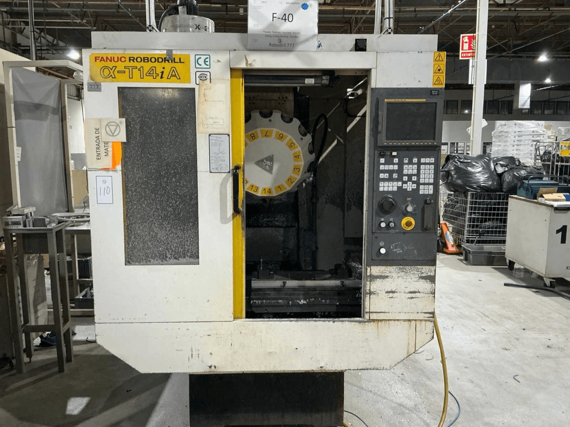 Вертикальний обробний центр FANUC ROBODRILL α-T14iB, вид спереду з панеллю керування та каруселлю інструментів.
