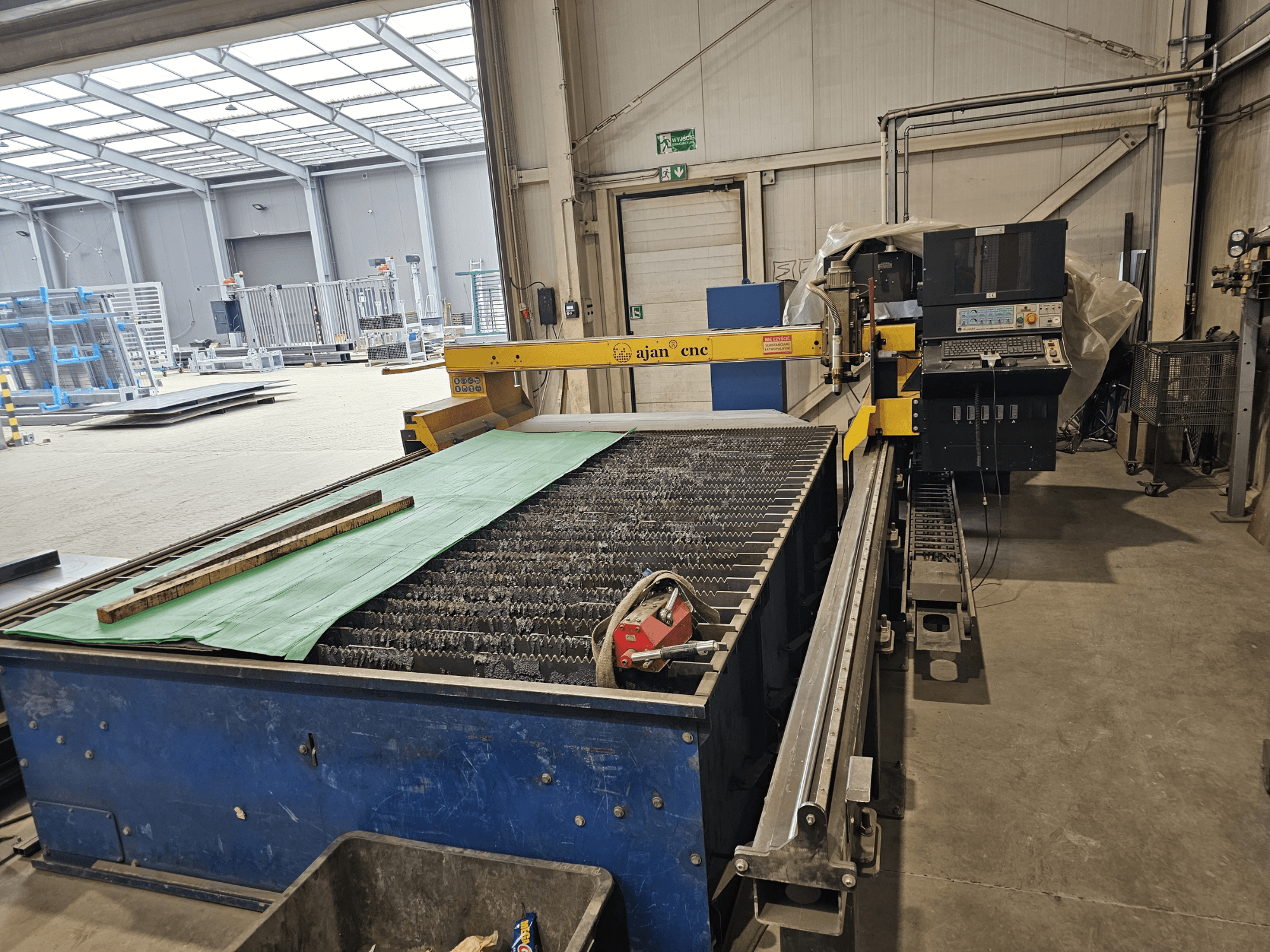 AJAN PP16011 Автомат для плазмового різання, вид збоку, зі столом для різання та панеллю керування, встановлений в умовах майстерні.