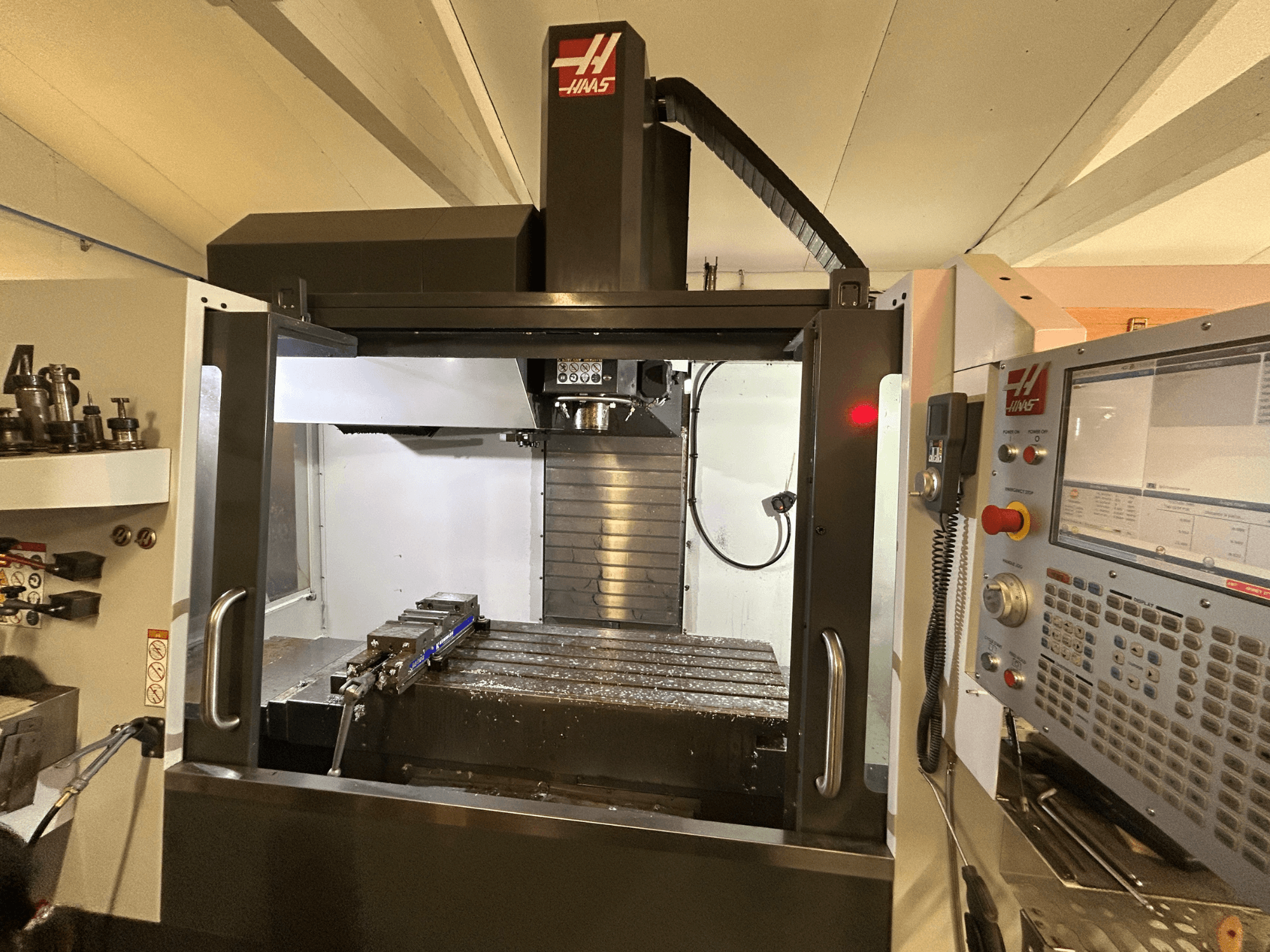 Вертикальний обробний центр HAAS VF-4SS, вид спереду, демонструє панель керування, тримач інструменту та робочу зону з металевою стружкою.