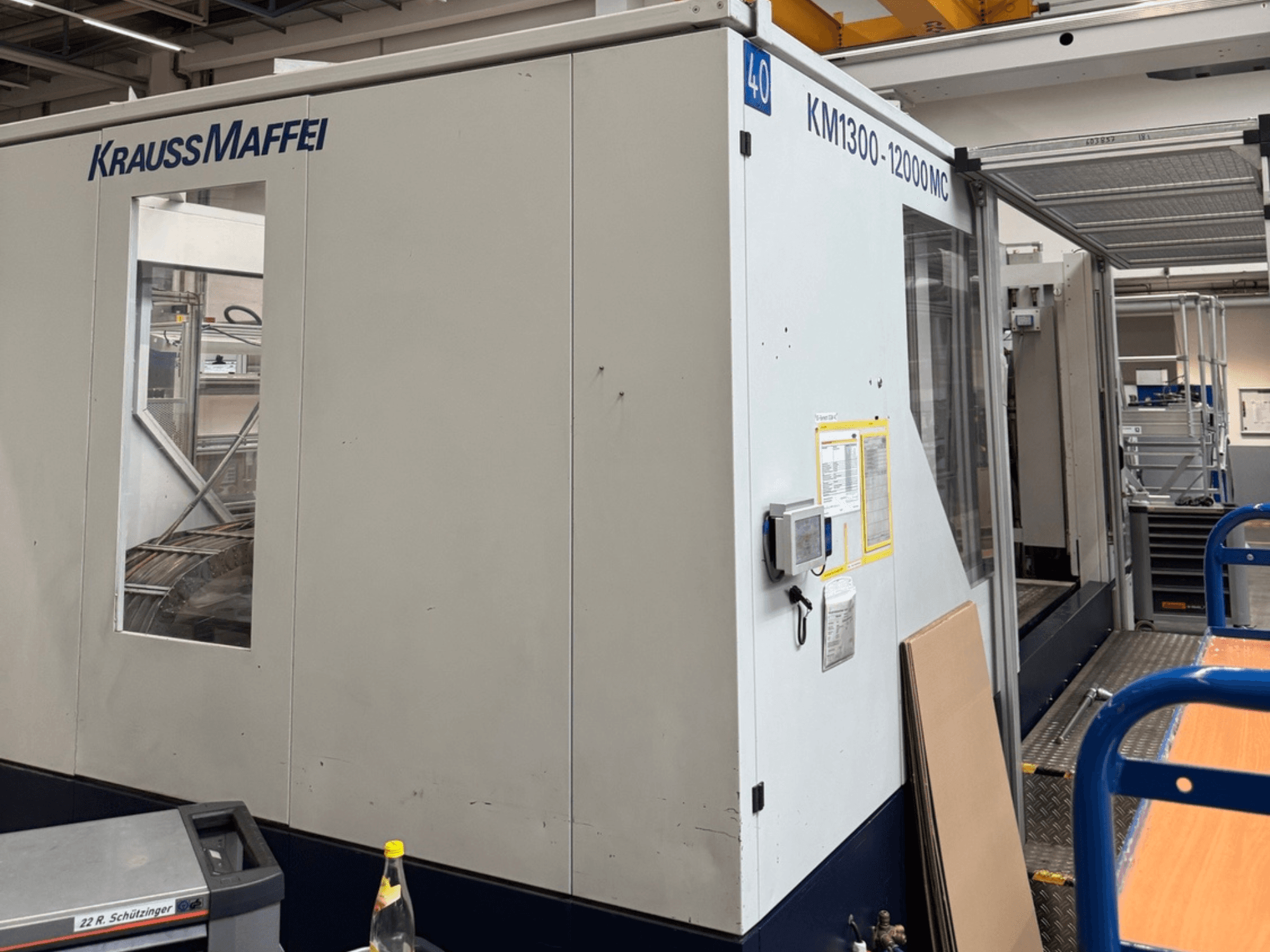 Термопластавтомат Krauss Maffei KM1300-12000 MC, вид збоку, демонструє панель керування та робочий простір.