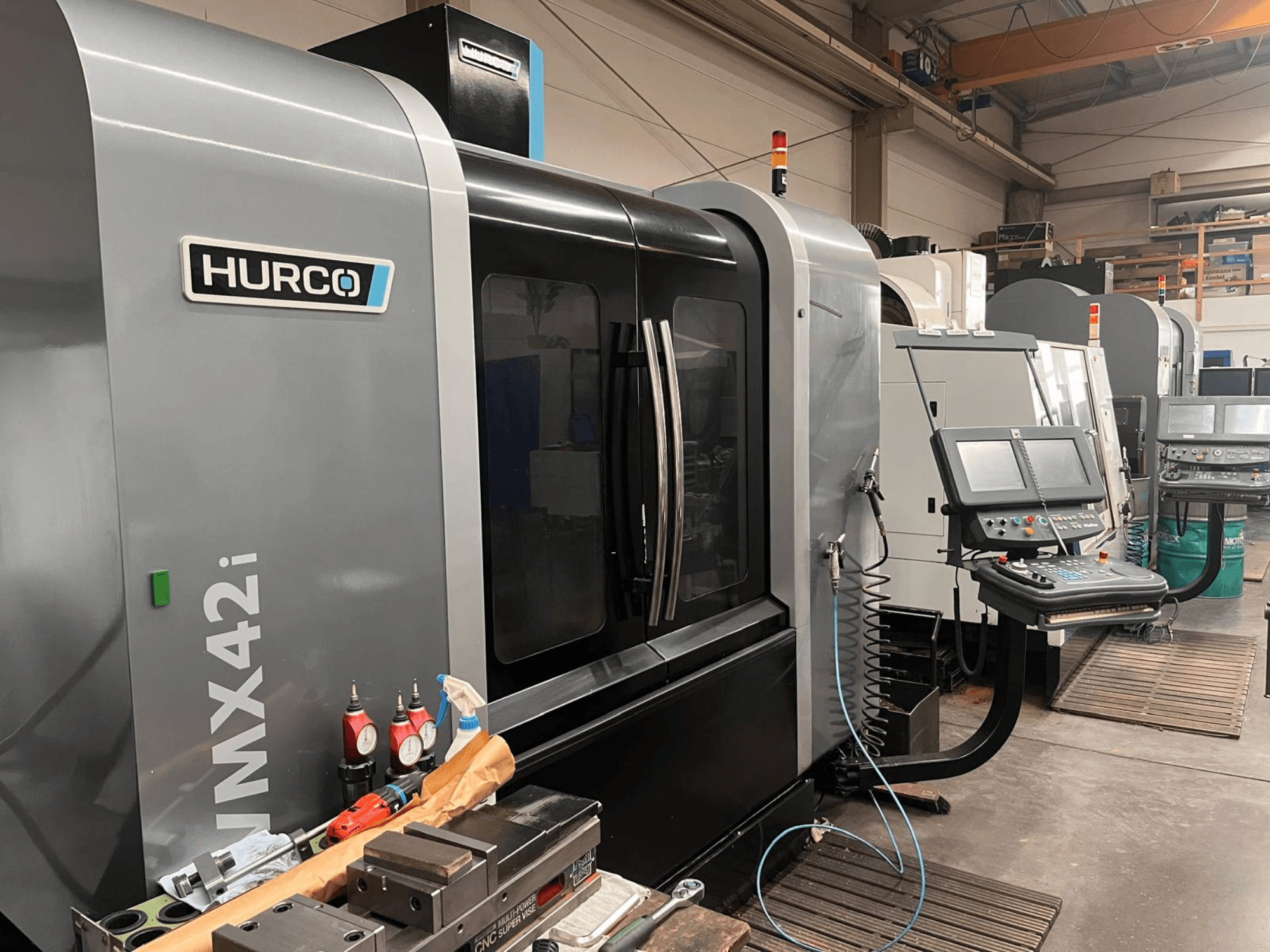 Верстат з ЧПК Hurco VMX42i в майстерні, вид спереду, з панеллю керування та різними інструментами на робочому столі.