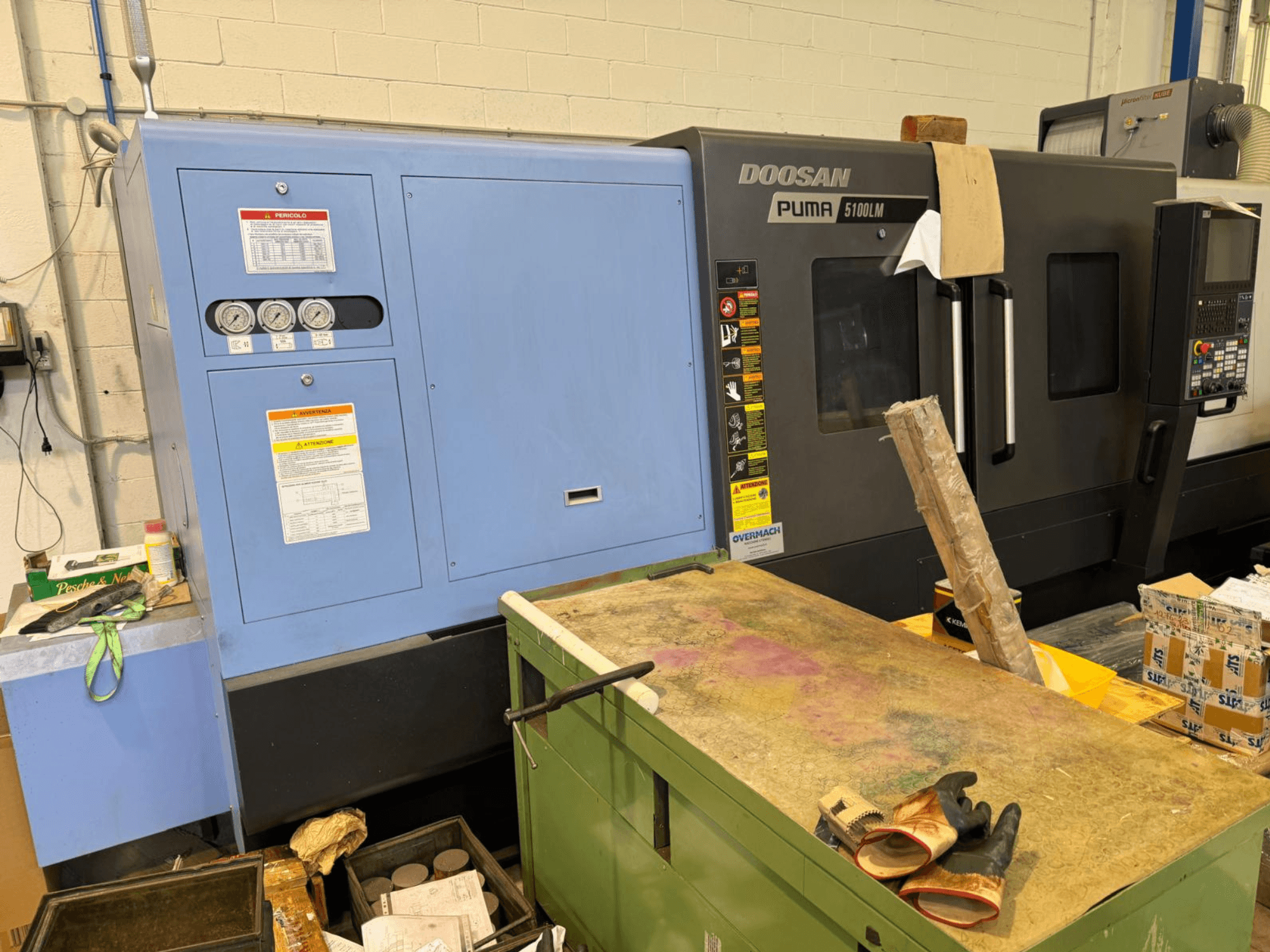 Верстат з ЧПК Doosan Puma 5100LM і панель керування, вид збоку. Манометри та попереджувальні написи видно на синьому блоці управління.