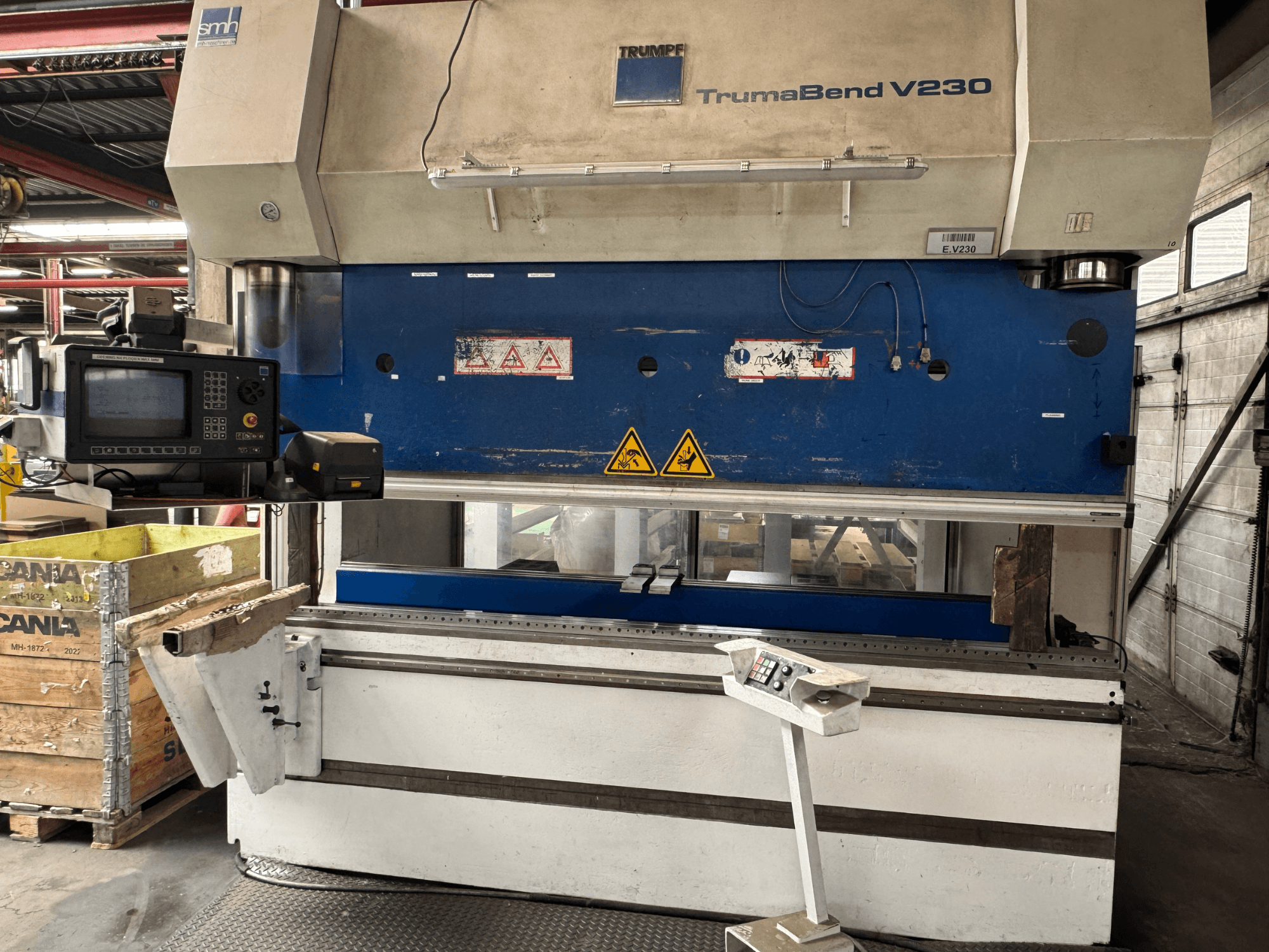 Прес TRUMPF TrumaBend V230, вид спереду з панеллю керування, попереджувальними написами та кронштейном для підтримки заготовки.