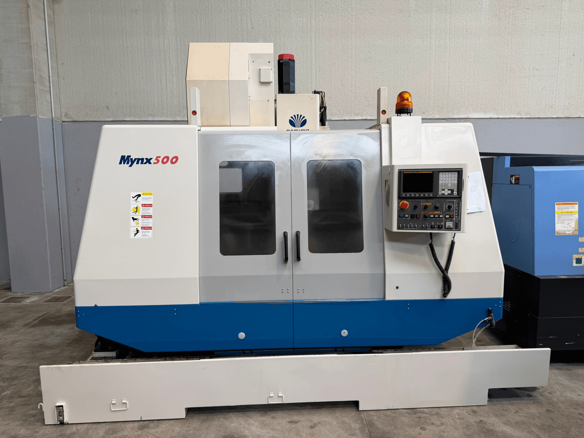 Вертикальний обробний центр DAEWOO MYNX 500 у фронтальному ракурсі з панеллю управління, сигнальними вогнями та прозорими дверцятами доступу.