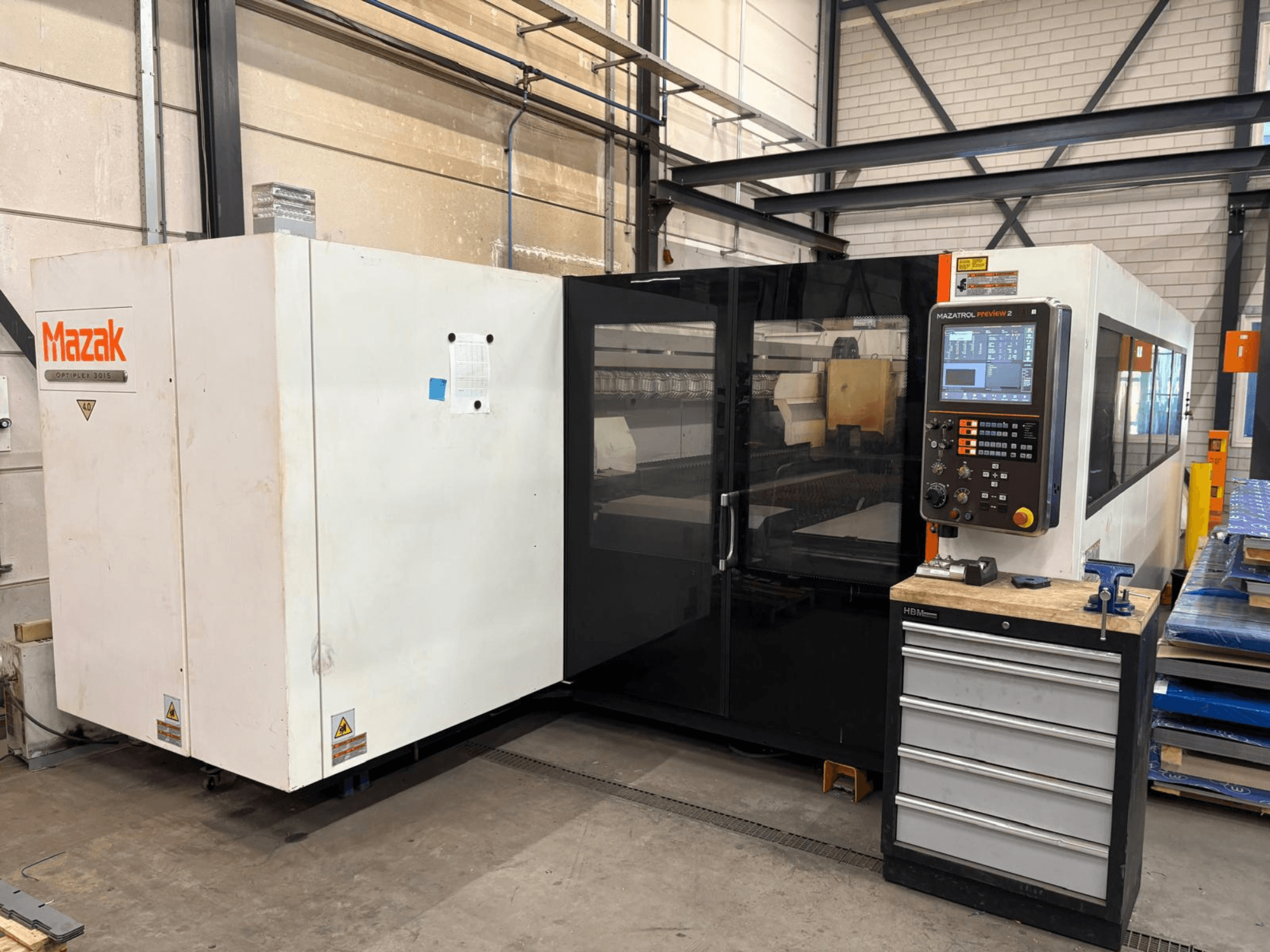 Лазерний верстат для різання CO2 Mazak Optiplex 3015, вид спереду, на якому видно панель керування та промислове розміщення.