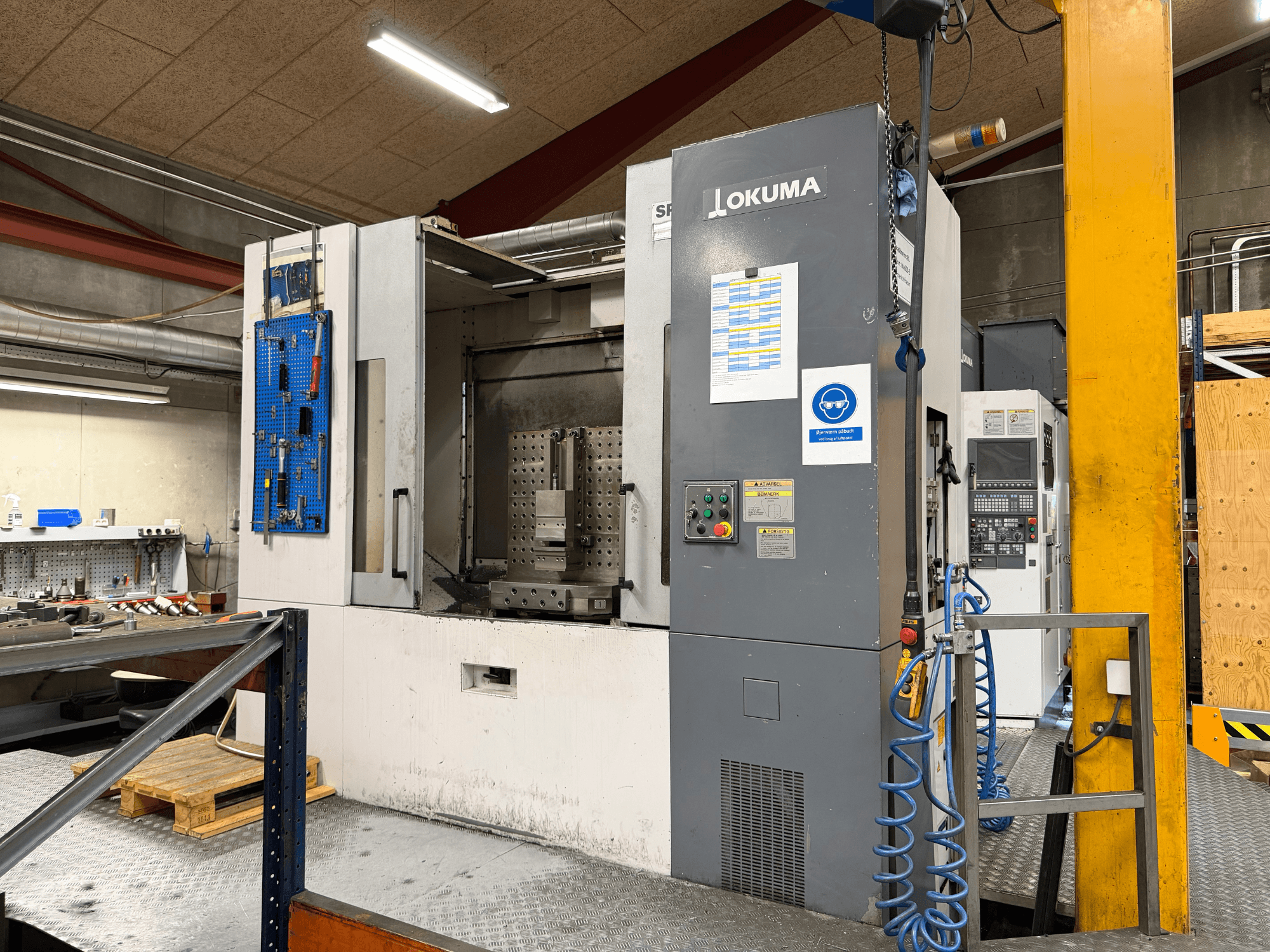 Горизонтальний обробний центр Okuma MA-600HB у цеху, вид спереду, на якому видно панель управління та робочу зону.