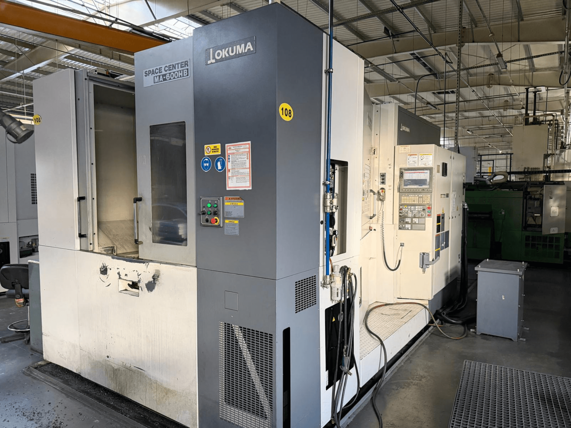 Горизонтальний обробний центр Okuma MA-600 HB, вид спереду, демонструє панель керування та зону різання з видимими слідами зносу.