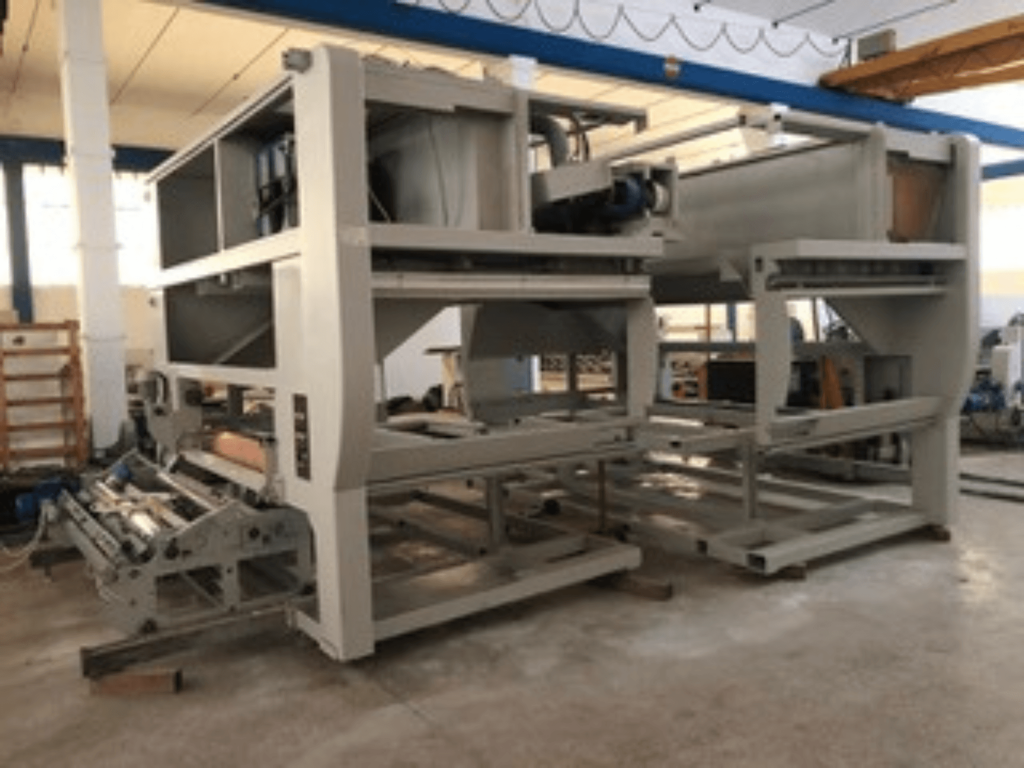 Промислова машина з декількома конвеєрними роликами і великою структурою; вид збоку, сірого кольору, розташована на добре освітленому заводі.