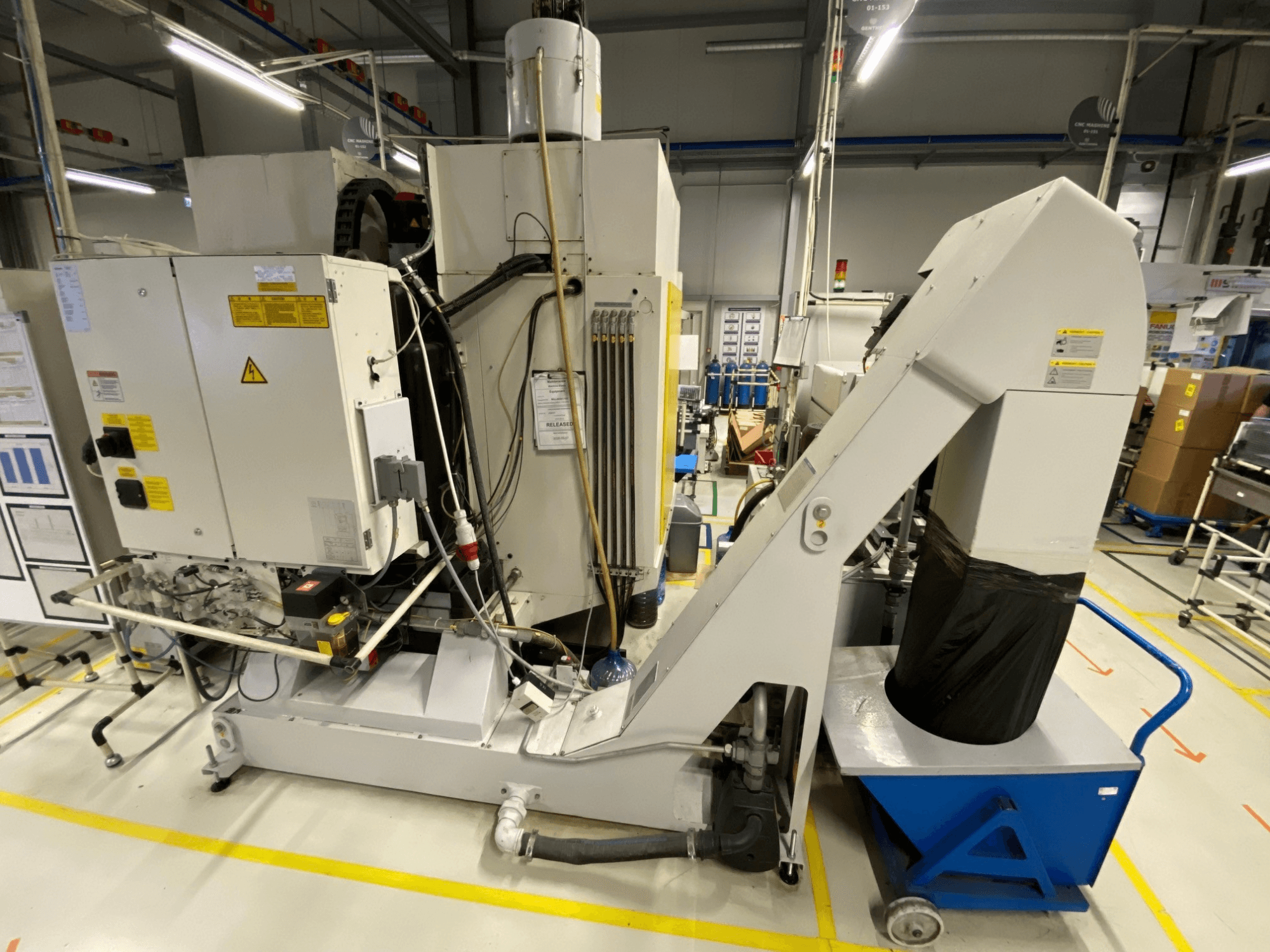 Вертикальний обробний центр FANUC ROBODRILL α-D21LiB у фронтальному ракурсі, на якому видно електричні компоненти та вихідний жолоб.